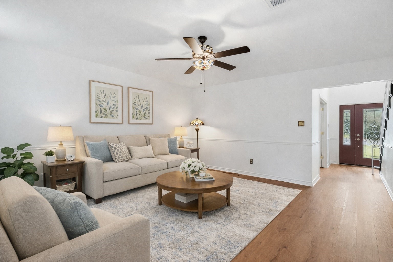 Virtually staged living room. Spacious living room with brick fireplace and stained glass ceiling fan. Virtually staged living room. Spacious living room with brick fireplace and stained glass ceiling fan.