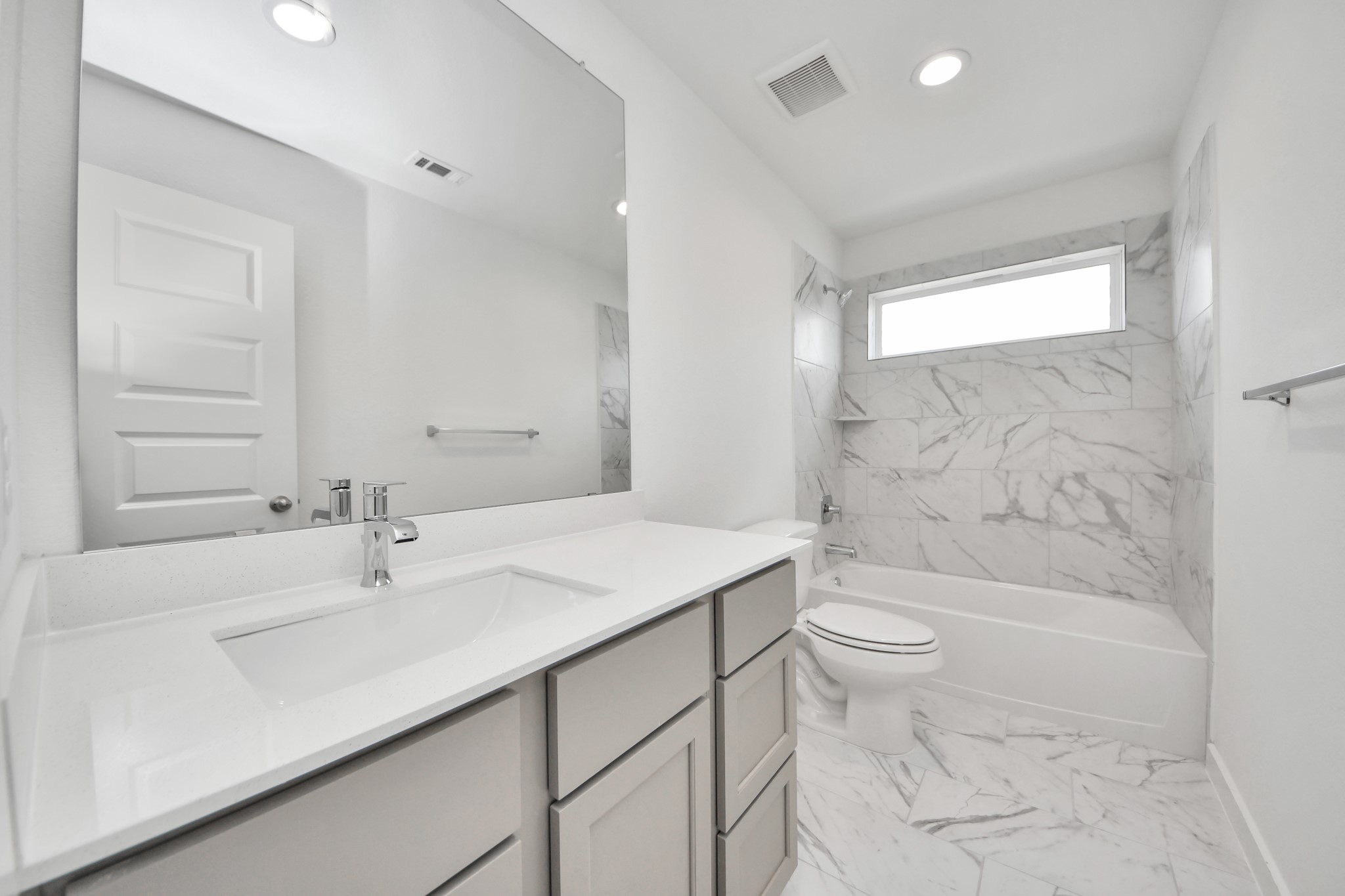 Secondary bath features tile flooring, bath/shower combo with tile surround, light stained wood cabinets, beautiful light countertop. Sample photo of completed home with similar floor plan. Actual colors and selections may vary.