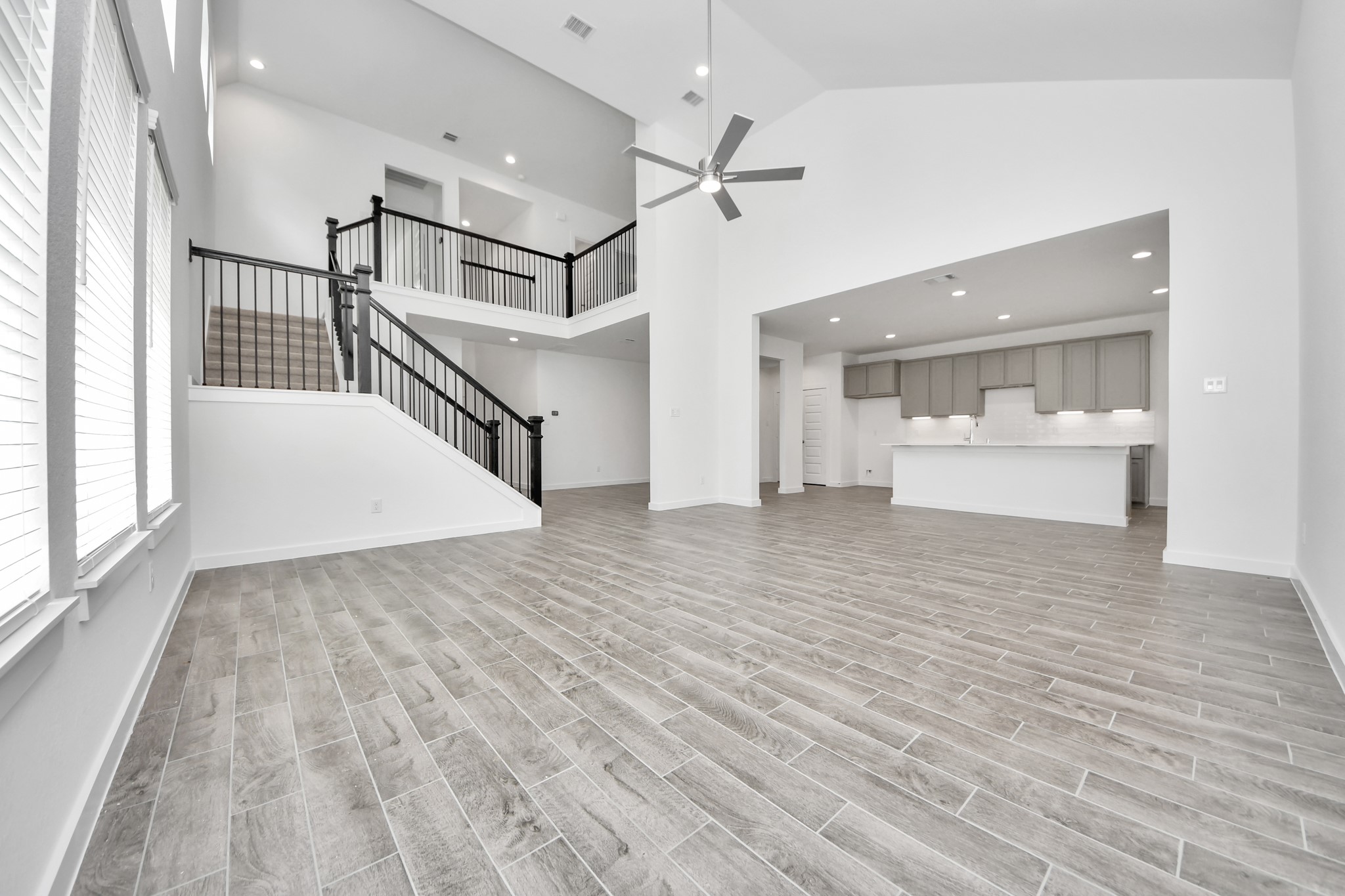 Relax and unwind in this inviting family room, illuminated by abundant natural light streaming in through tall windows, complemented by high ceilings and stunning flooring. Stay comfortable year-round with the gentle breeze from the ceiling fan, creating the perfect atmosphere for family gatherings. Sample photo of completed home with similar floor plan. Actual colors and selections may vary.