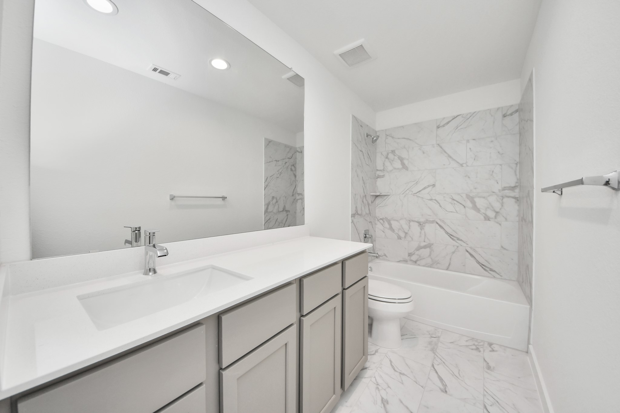 Secondary bath features tile flooring, bath/shower combo with tile surround, light stained wood cabinets, beautiful light countertop. Sample photo of completed home with similar floor plan. Actual colors and selections may vary.