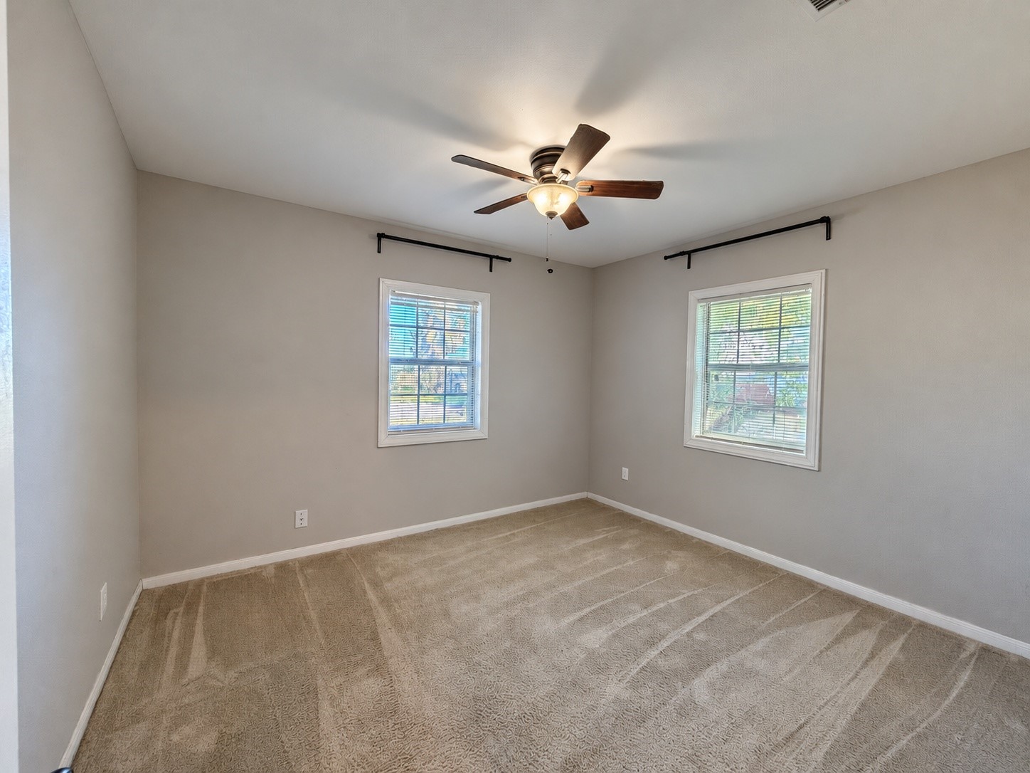 Bedroom 1 (approx. 11x12) with a ceiling fan, two windows and carpet.