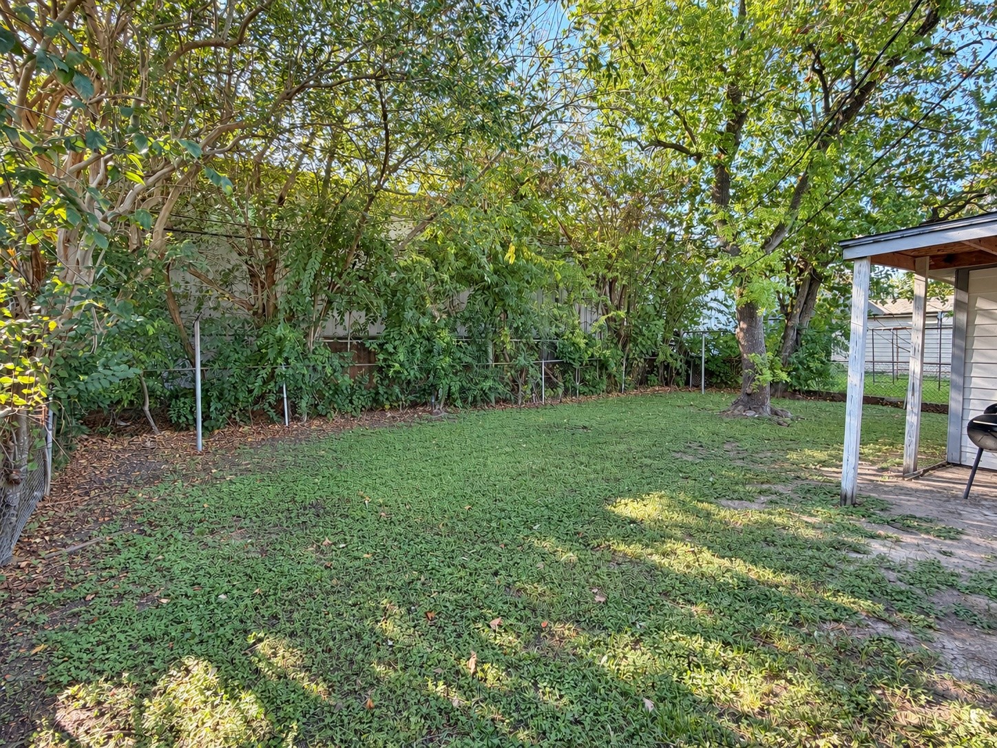 Spacious backyard with mature trees.