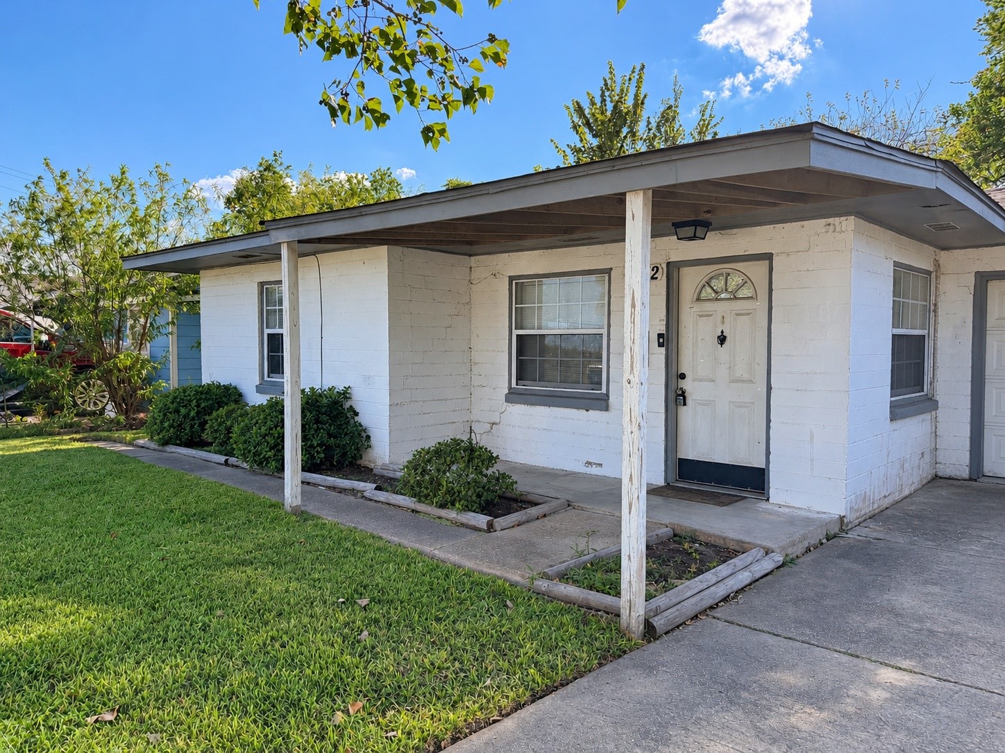 Single-story brick exterior with a covered front porch and green lawn. Single-story brick exterior with a covered front porch and green lawn.