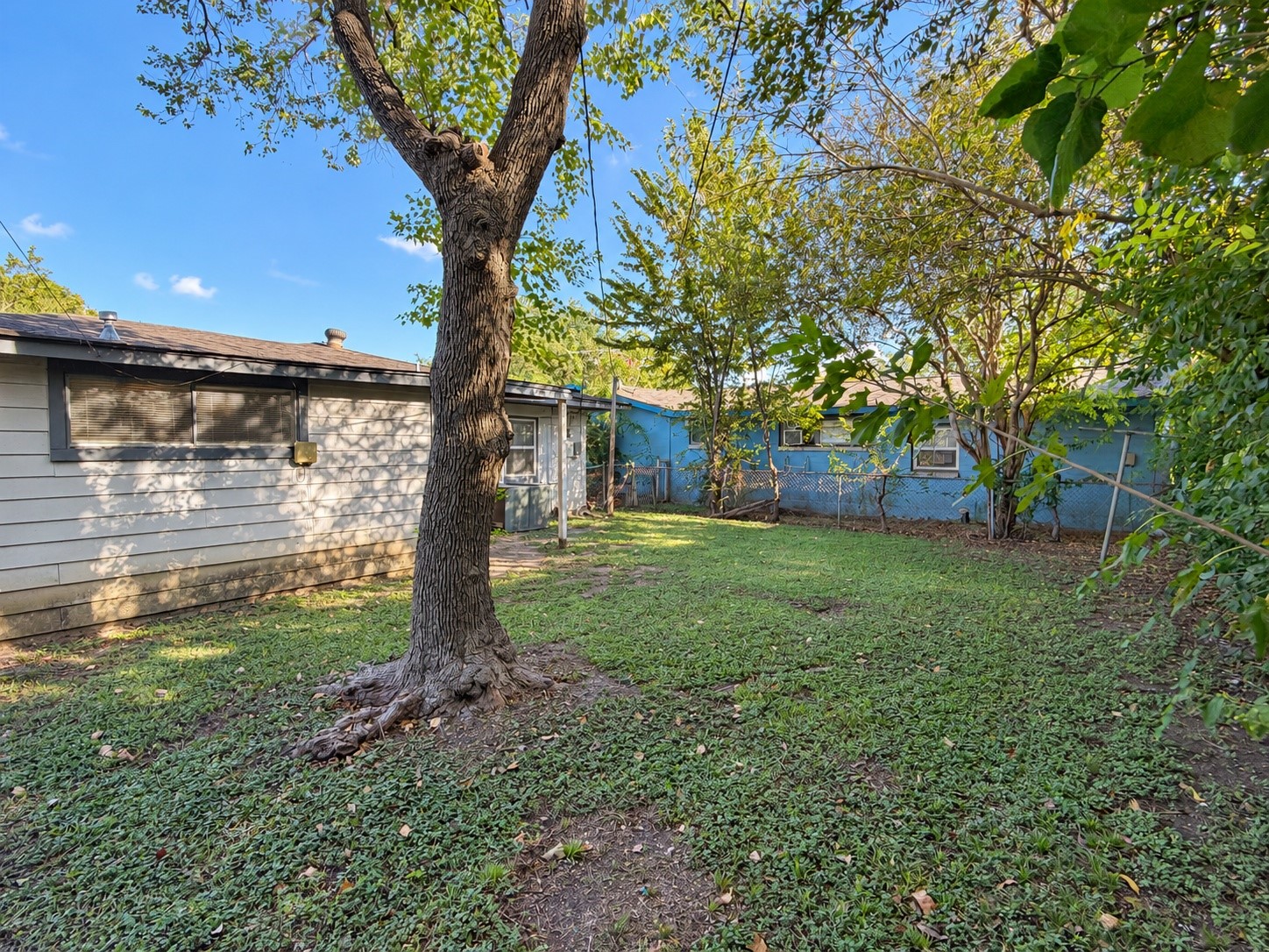 Large grassy backyard with shade trees on a 4,500 sq ft lot.