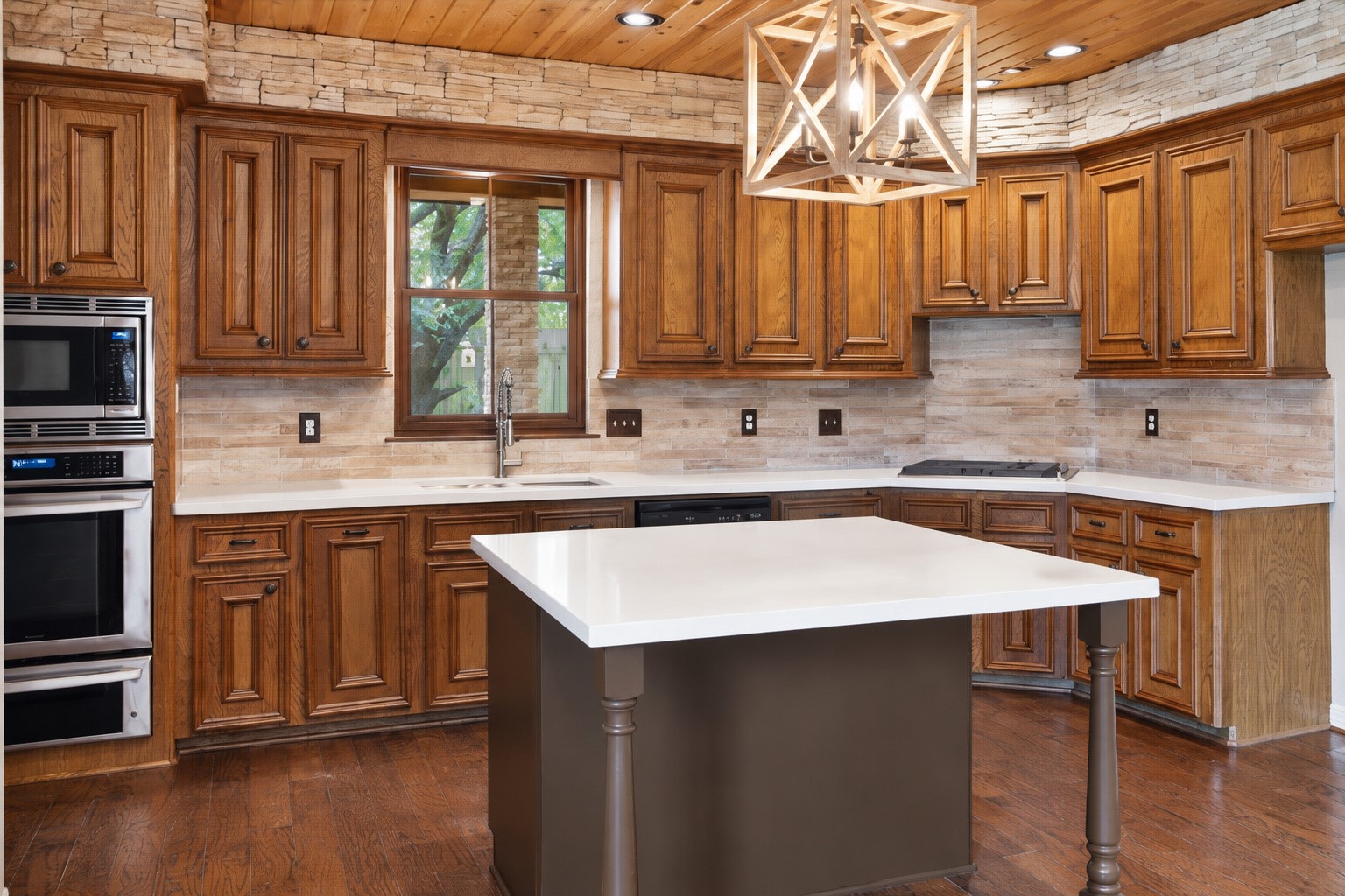 Renovated kitchen with quartz island and countertops, stunning backsplash and rich cabinets.