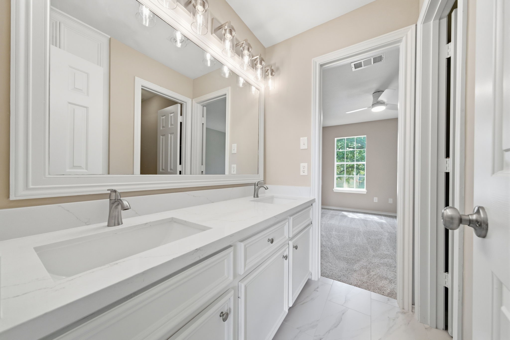 The renovated secondary bath offers a bright vanity area with double sinks, generous cabinetry and plenty of counter space for everyday routines. The renovated adjoining tub and shower area is finished in classic white tile for a timeless look.
