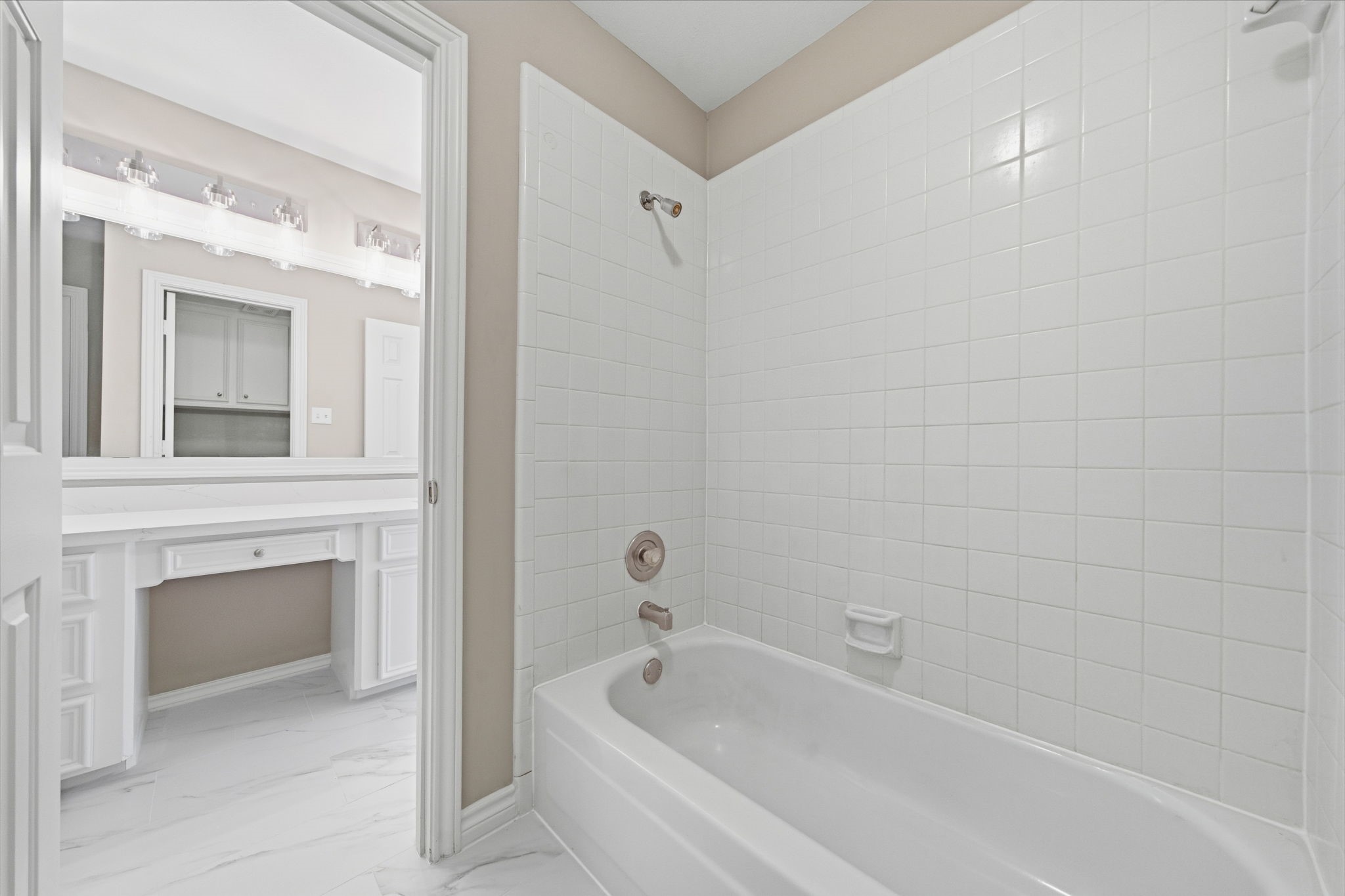 The adjoining tub and shower area is finished in classic white tile for a timeless look. Ample storage makes the bathroom as functional as it is bright.