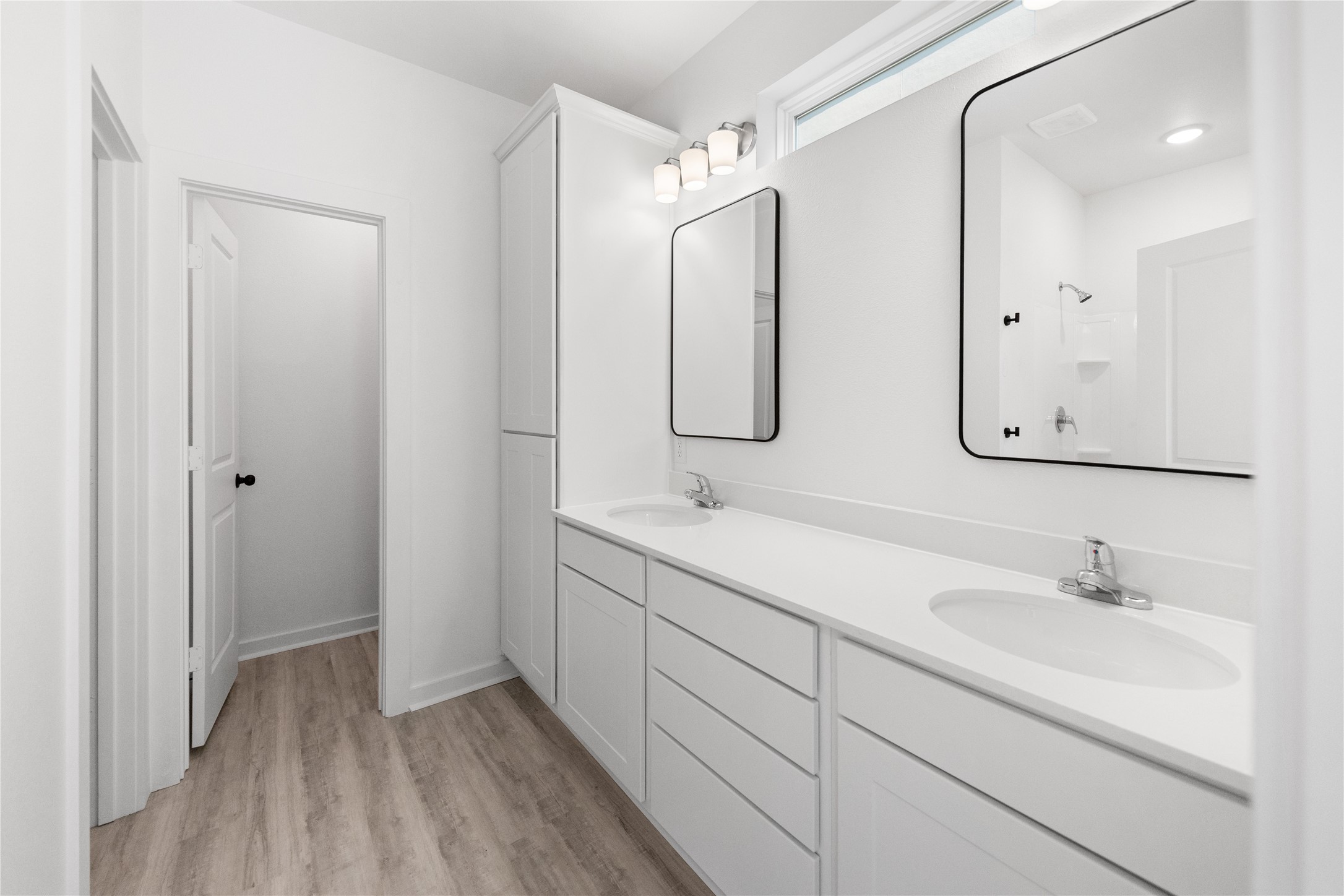 Primary bathroom with two vanity sinks and tasteful blk accent lighting