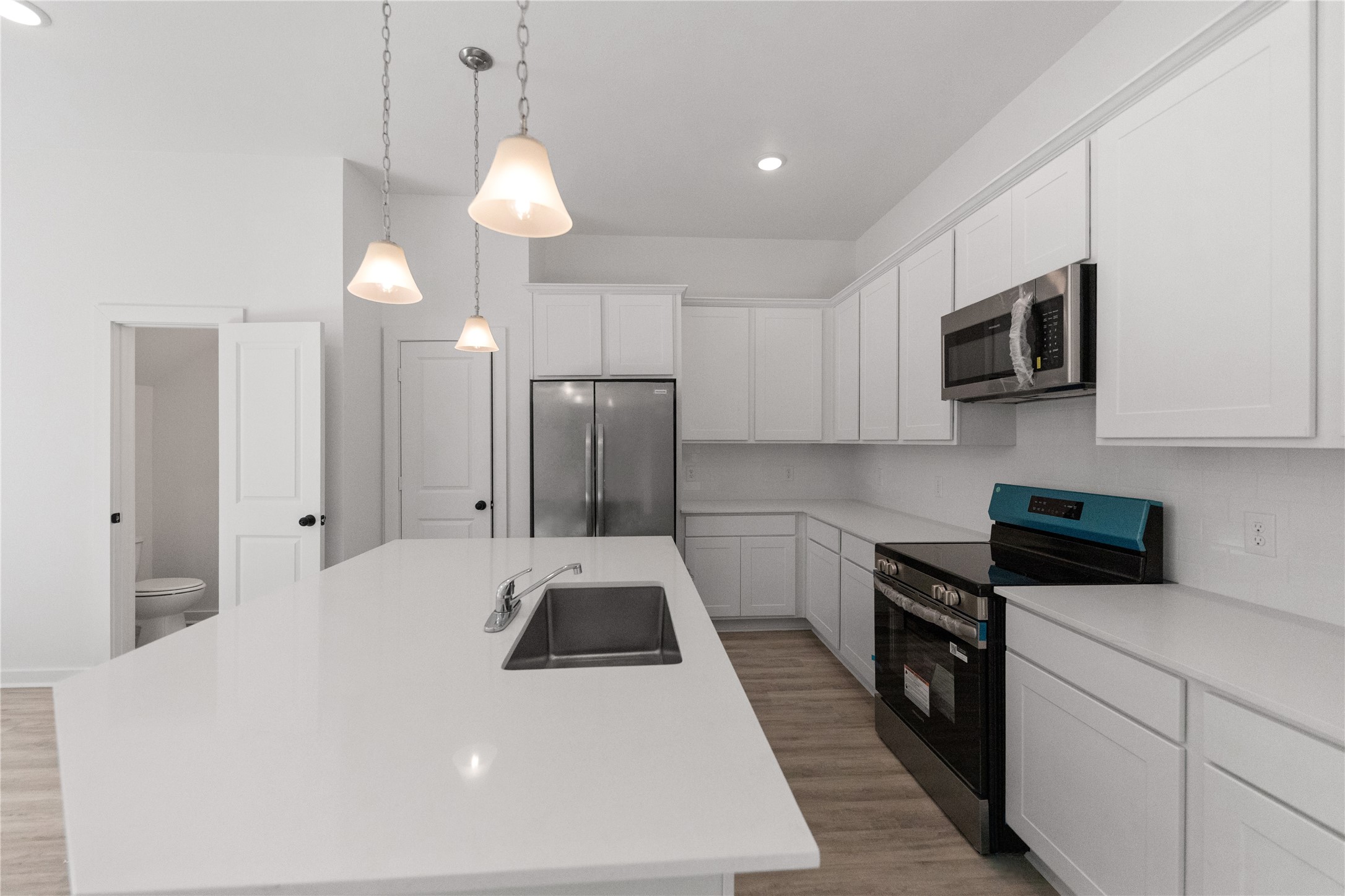 Stainless steel appliances and tasteful pendant lighting over isalnd