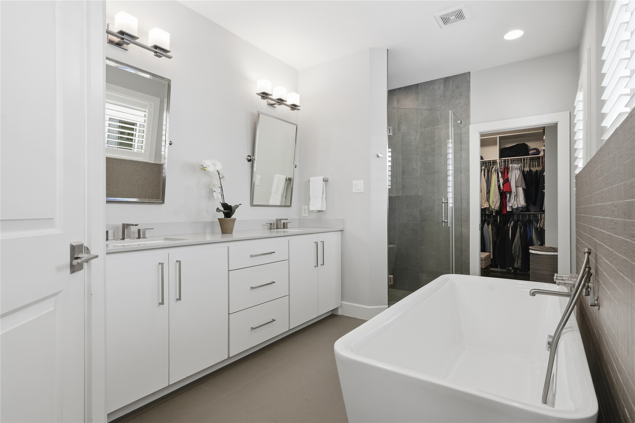 The spa-inspired primary bath features dual vanities, a freestanding soaking tub, a spacious walk-in shower, and a private water closet.