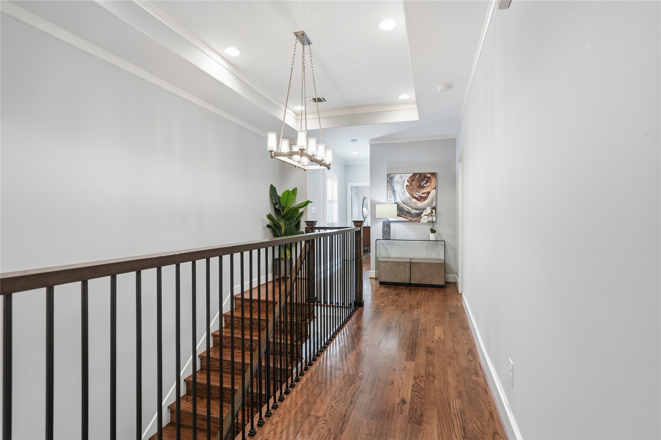 Thoughtfully designed second-floor hallway showcases hardwood flooring, elevated ceiling details, and an airy layout that enhances the home's flow.