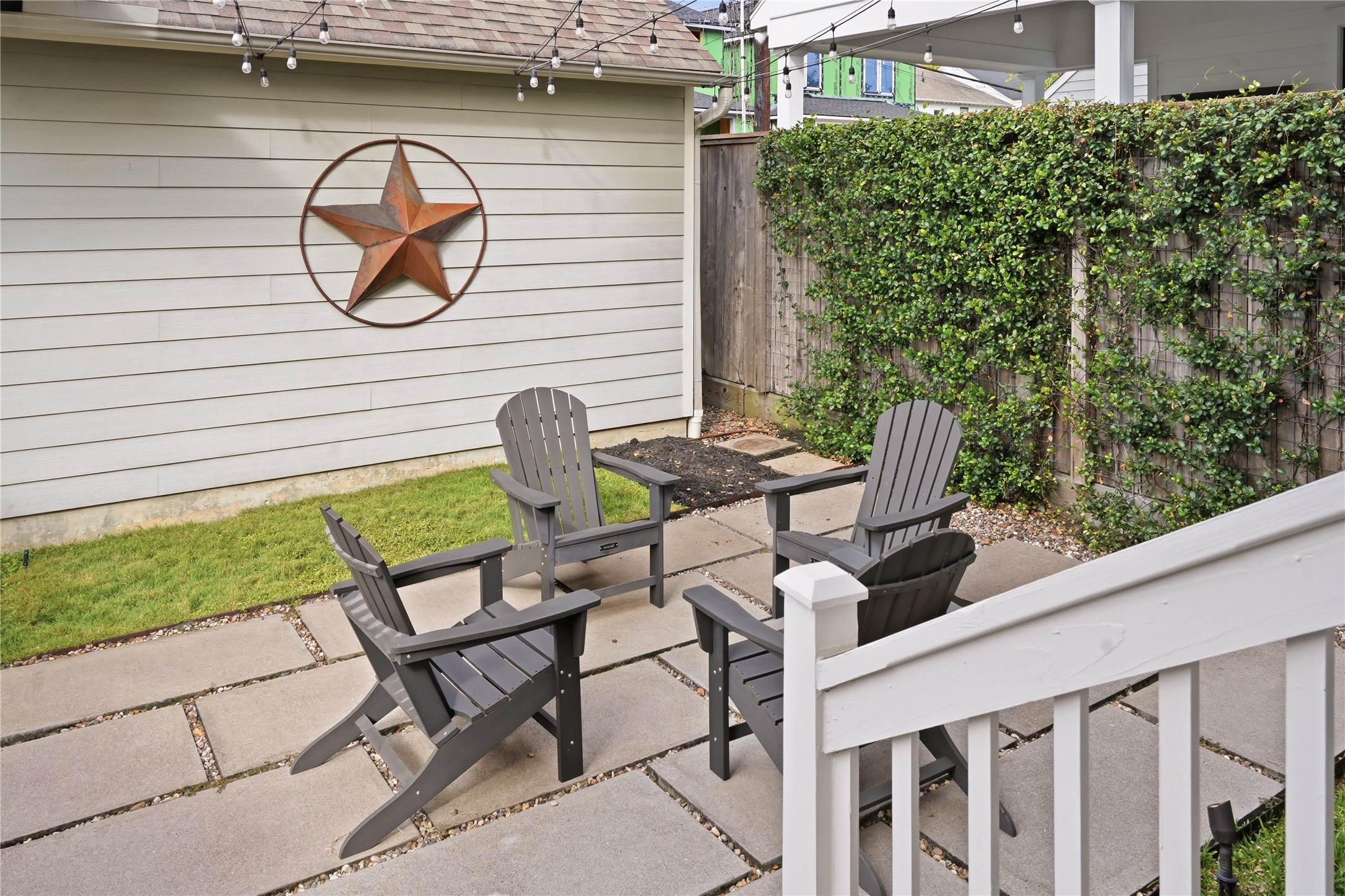 The charming backyard retreat features a spacious patio, caf lighting, and ample room for entertaining or unwinding outdoors.