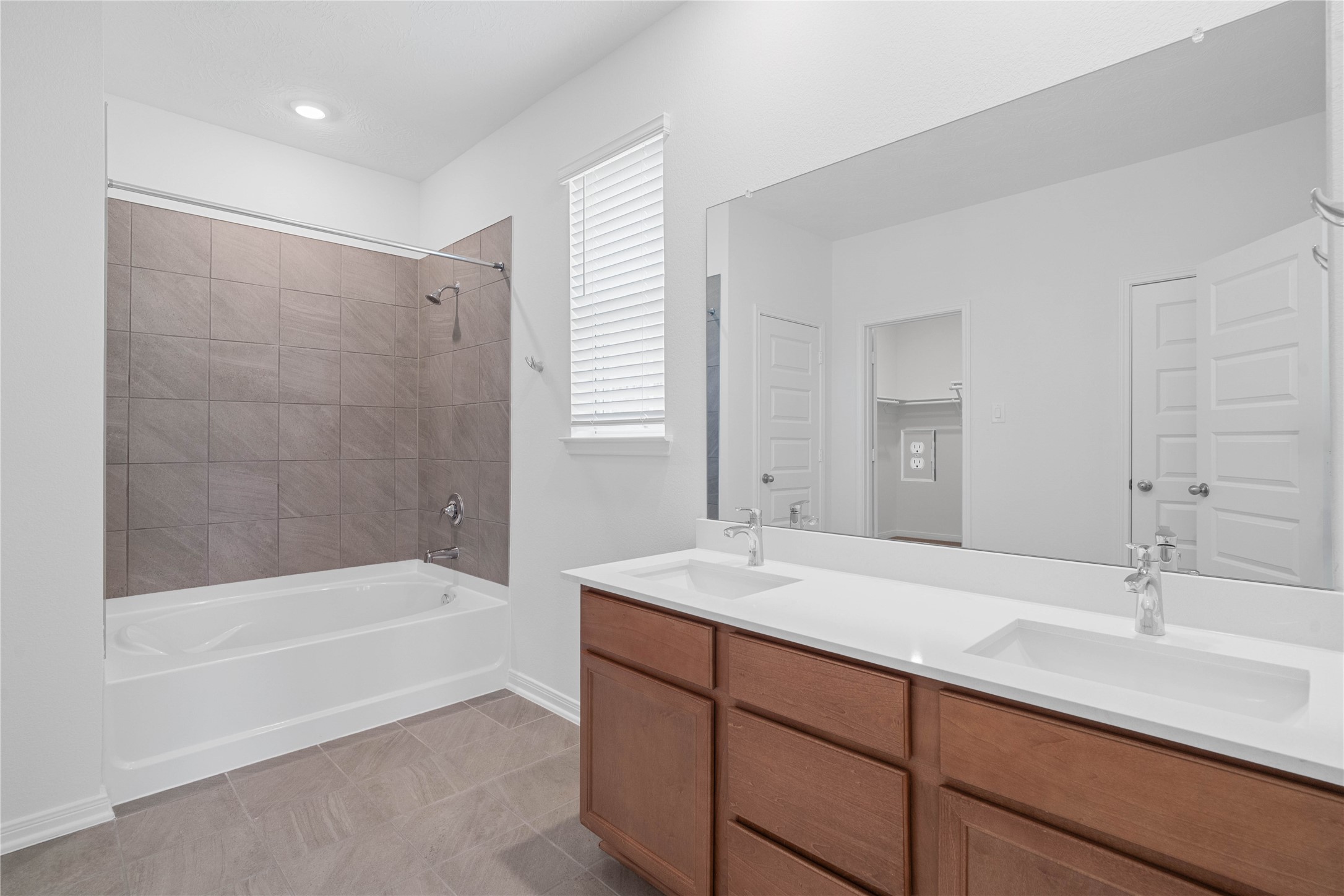 This stunningly updated primary bathroom is truly move-in ready! It features stained cabinetry with light countertops, dual sinks, a large mirror, high ceilings, custom paint, tub/shower combination with tile surround, and sleek modern finishes throughout.