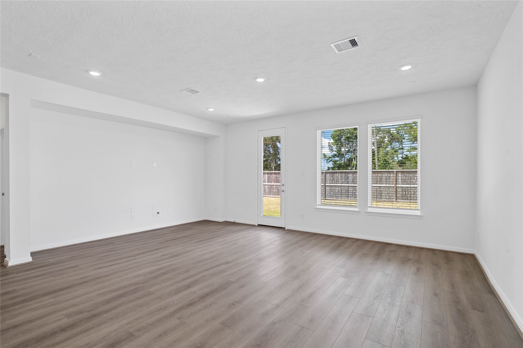 Sun-drenched living room boasting a dedicated architectural niche for seamless TV mounting and media storage.