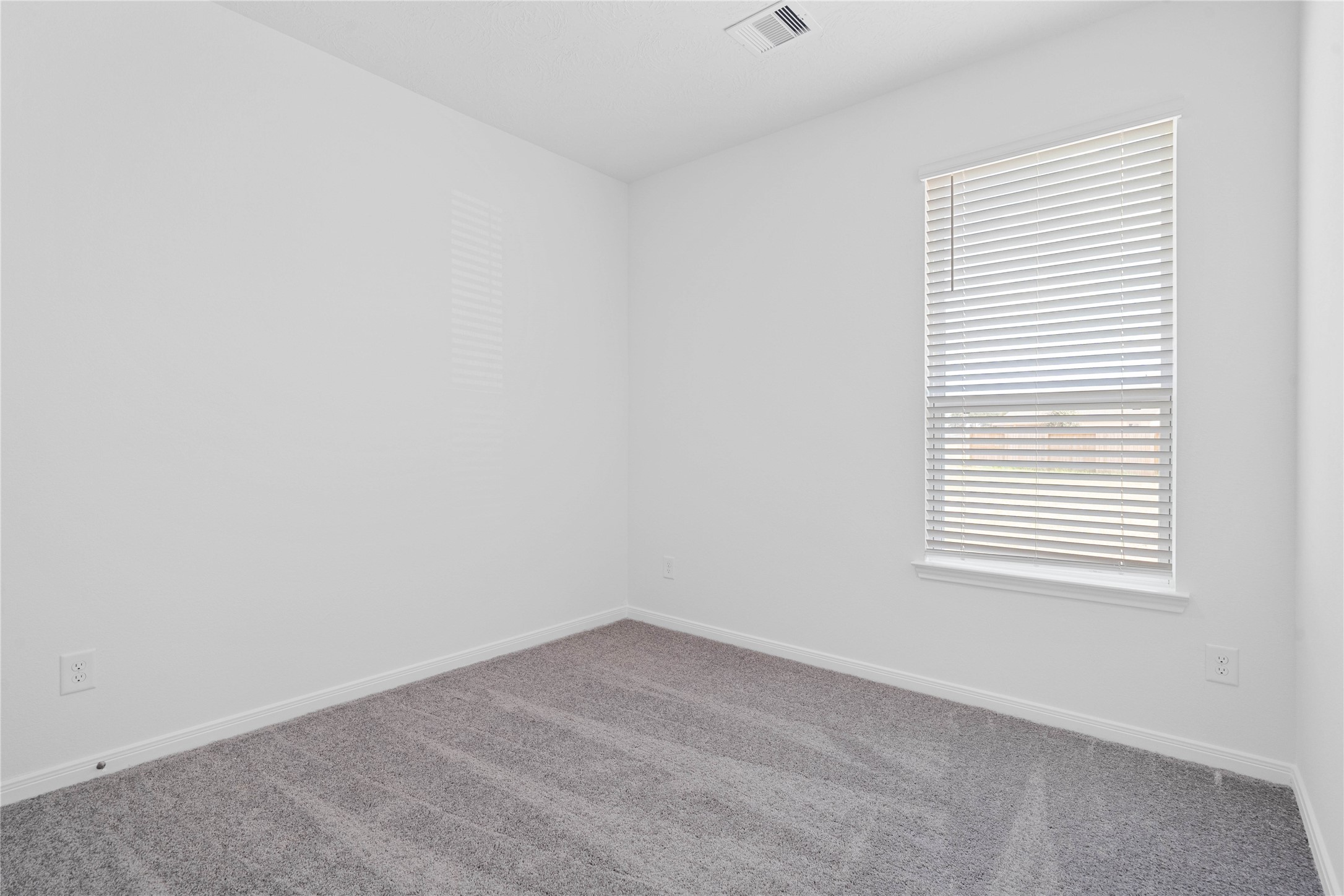 Tucked peacefully in the front of the home is this secondary bedroom! It offers comfort and style with plush carpeting, neutral paint tones, recessed lighting, a large window with blinds, and an ample sized closet.