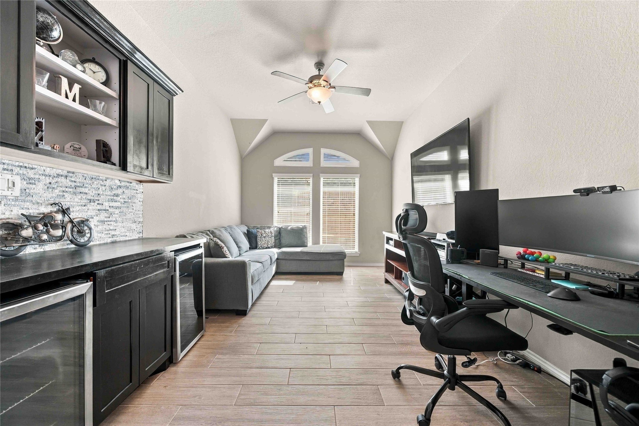 Versatile flex space featuring built-in cabinetry with a  bar area with mini fridges.