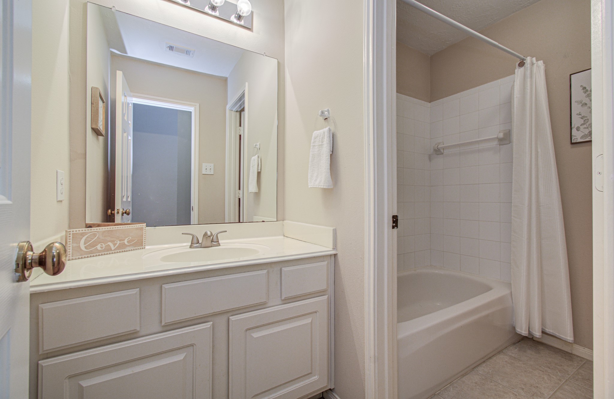 Convenient upstairs secondary bathroom features a spacious vanity with storage and a tub/shower combination.