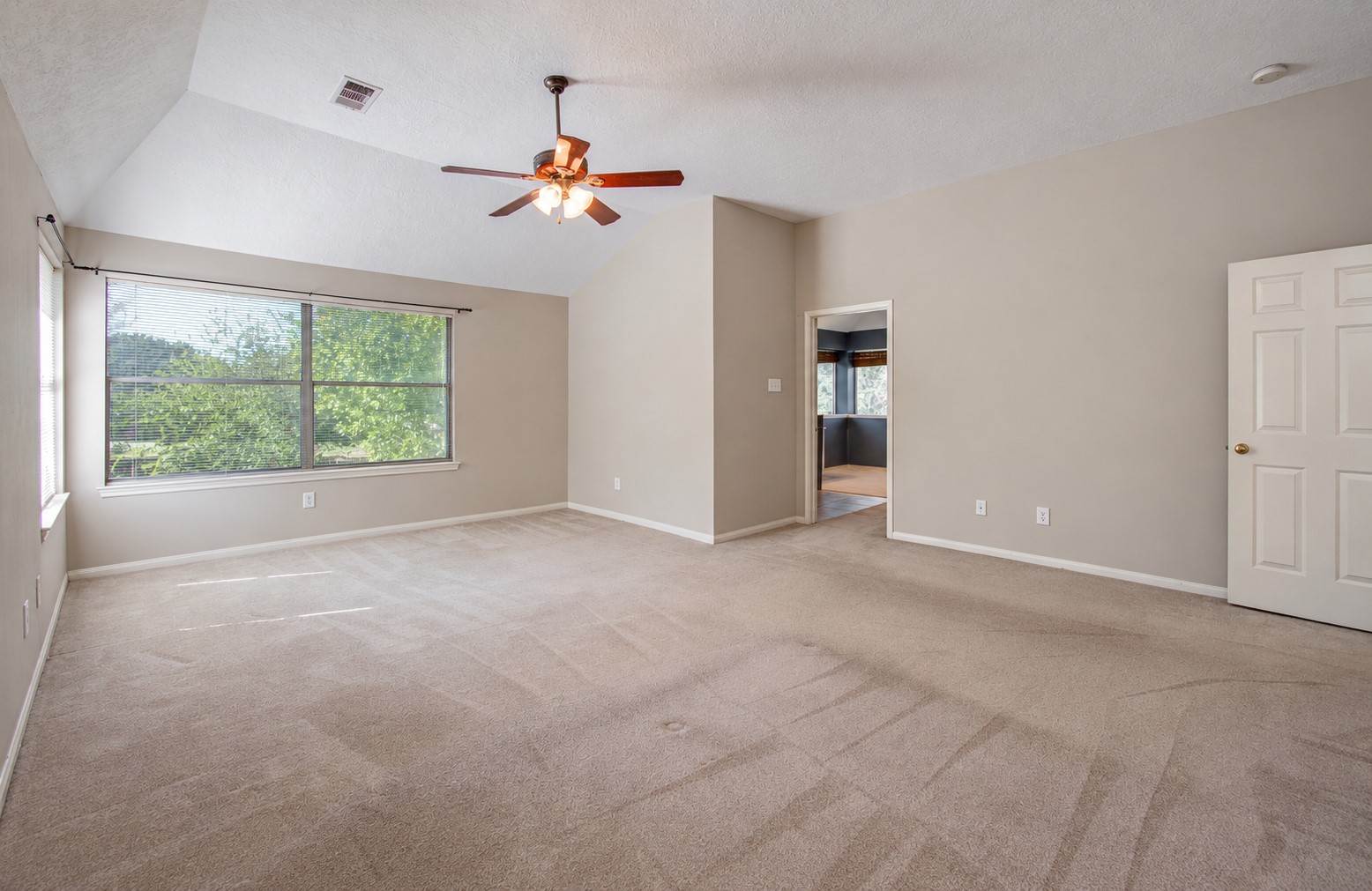 Spacious upstairs primary retreat offers room for substantial bedroom furniture and a comfortable sitting area, with windows bringing in natural light.