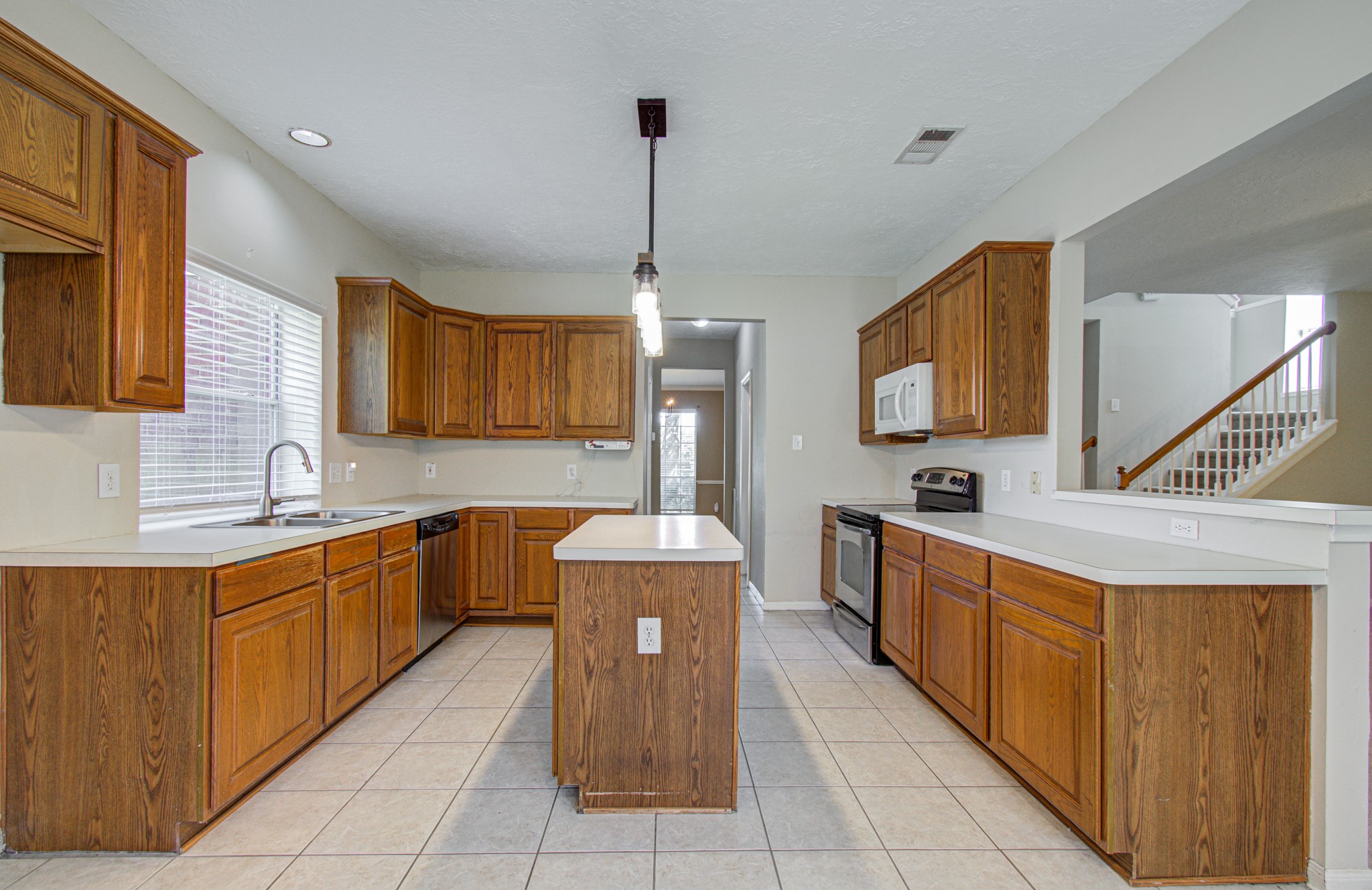 Island kitchen features abundant wood cabinetry, generous counter space, a double sink and convenient access to the family room and breakfast nook.