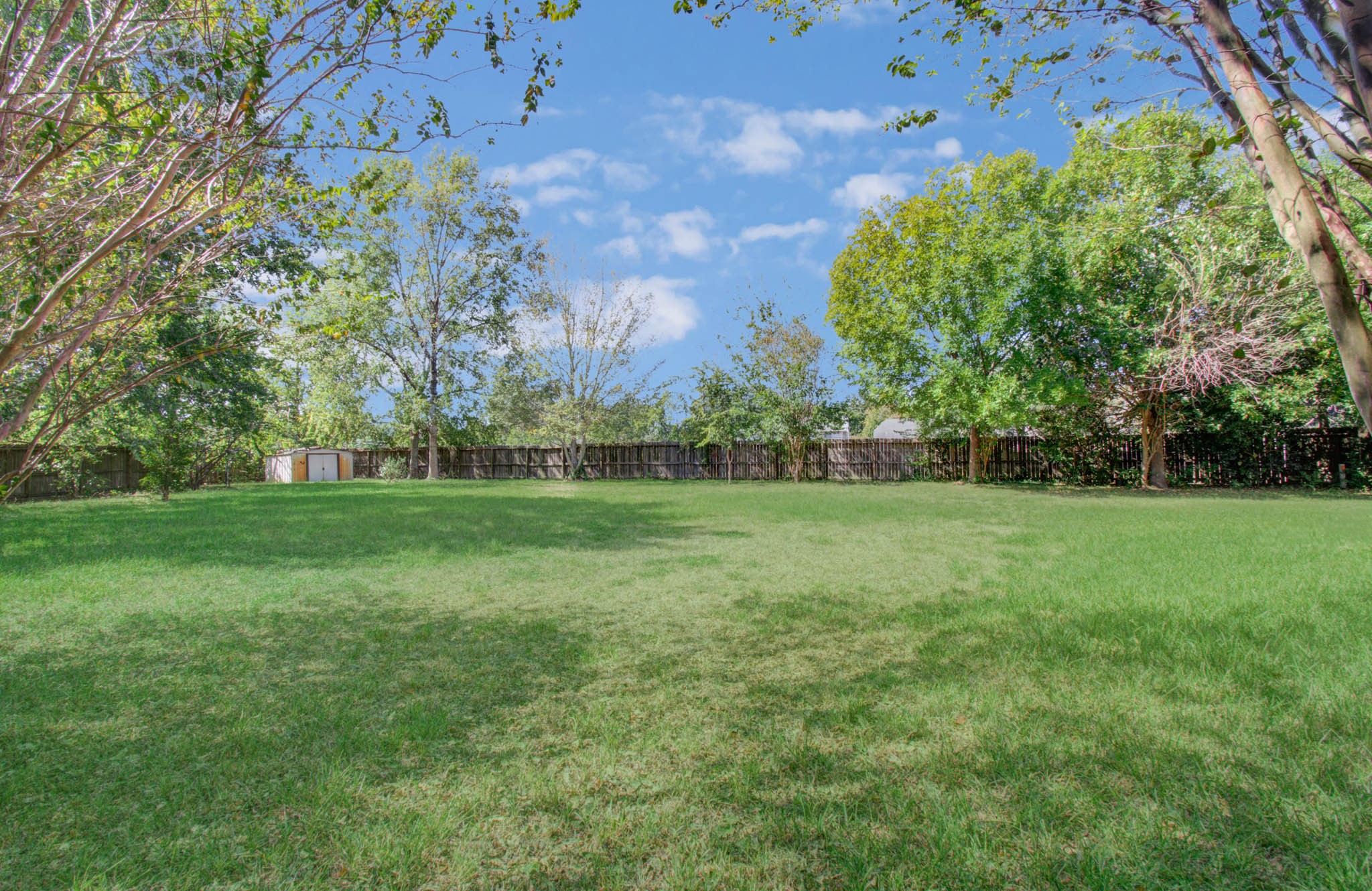 Wide-open green space framed by mature trees offers a wonderful setting for backyard gatherings, playtime or simply enjoying a little breathing room.