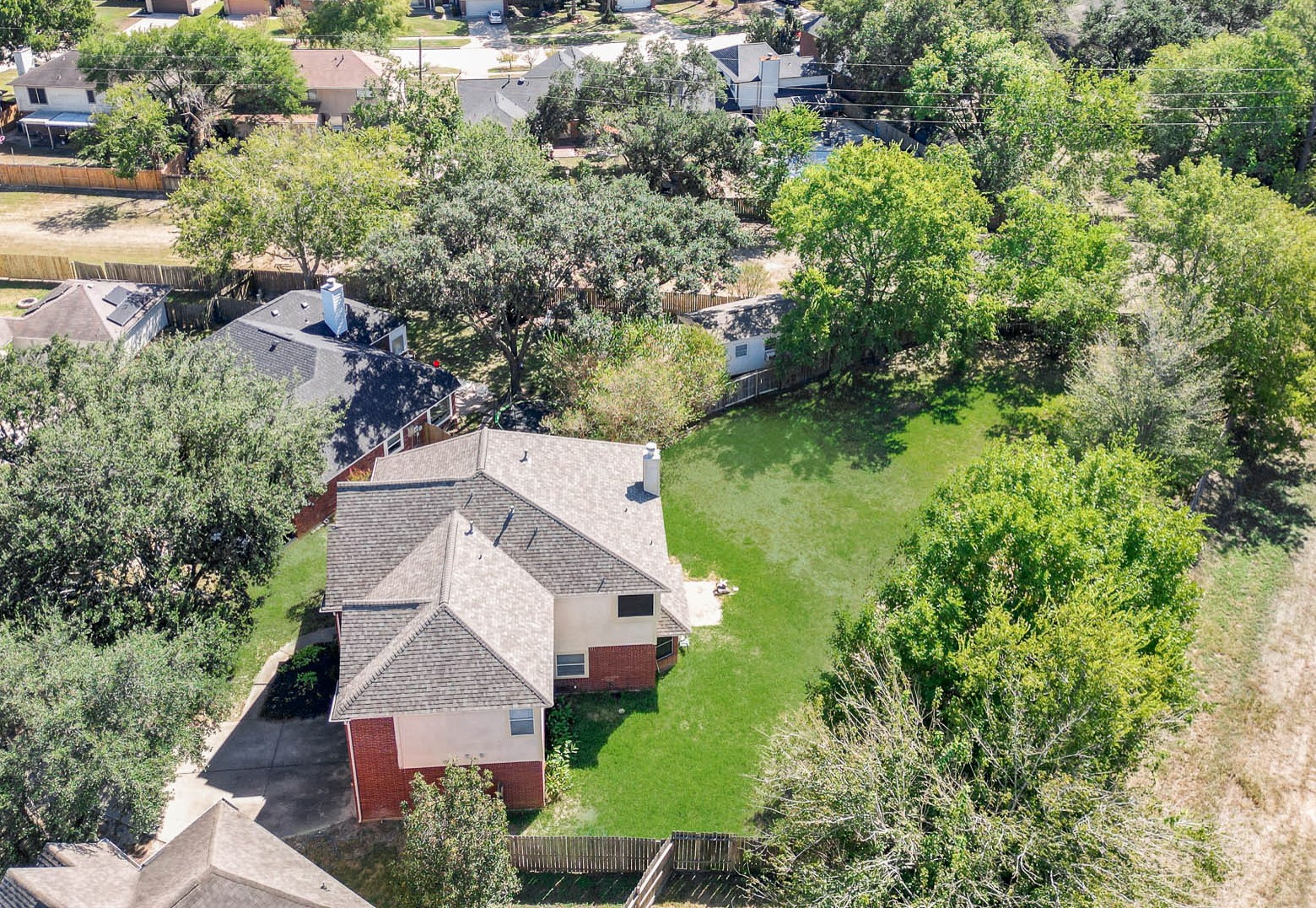 A bird's-eye view showcases the impressive backyard, mature trees and generous outdoor space surrounding the home.
