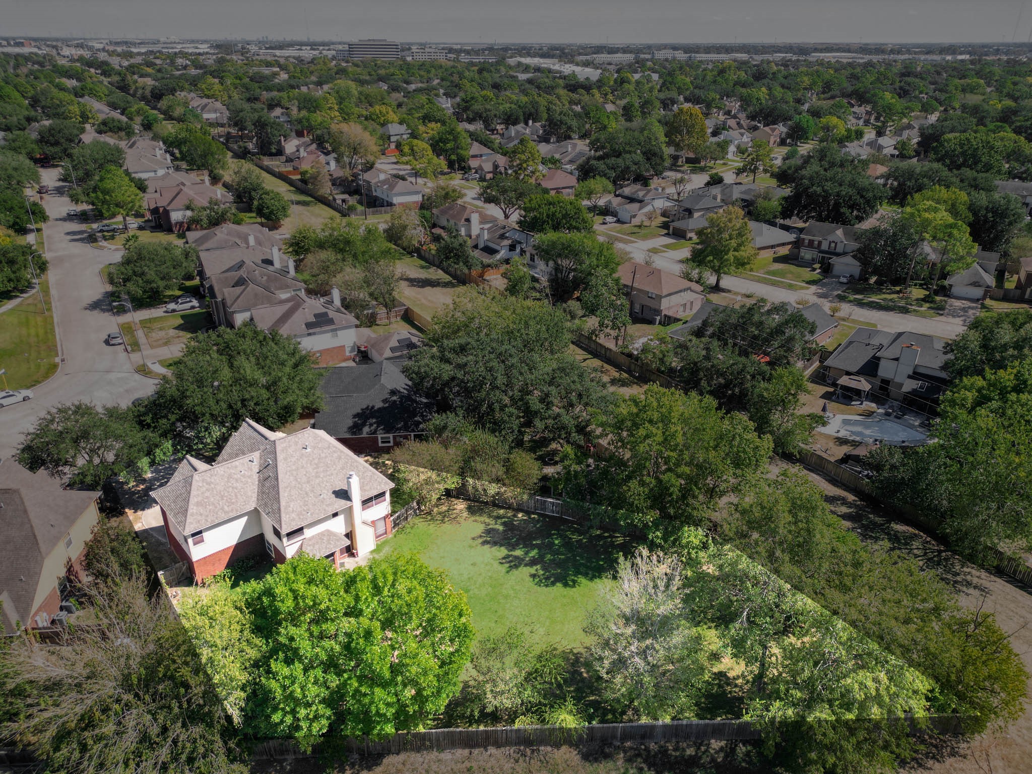 Aerial perspective highlights the home's setting among mature trees and the impressive backyard extending behind the property.