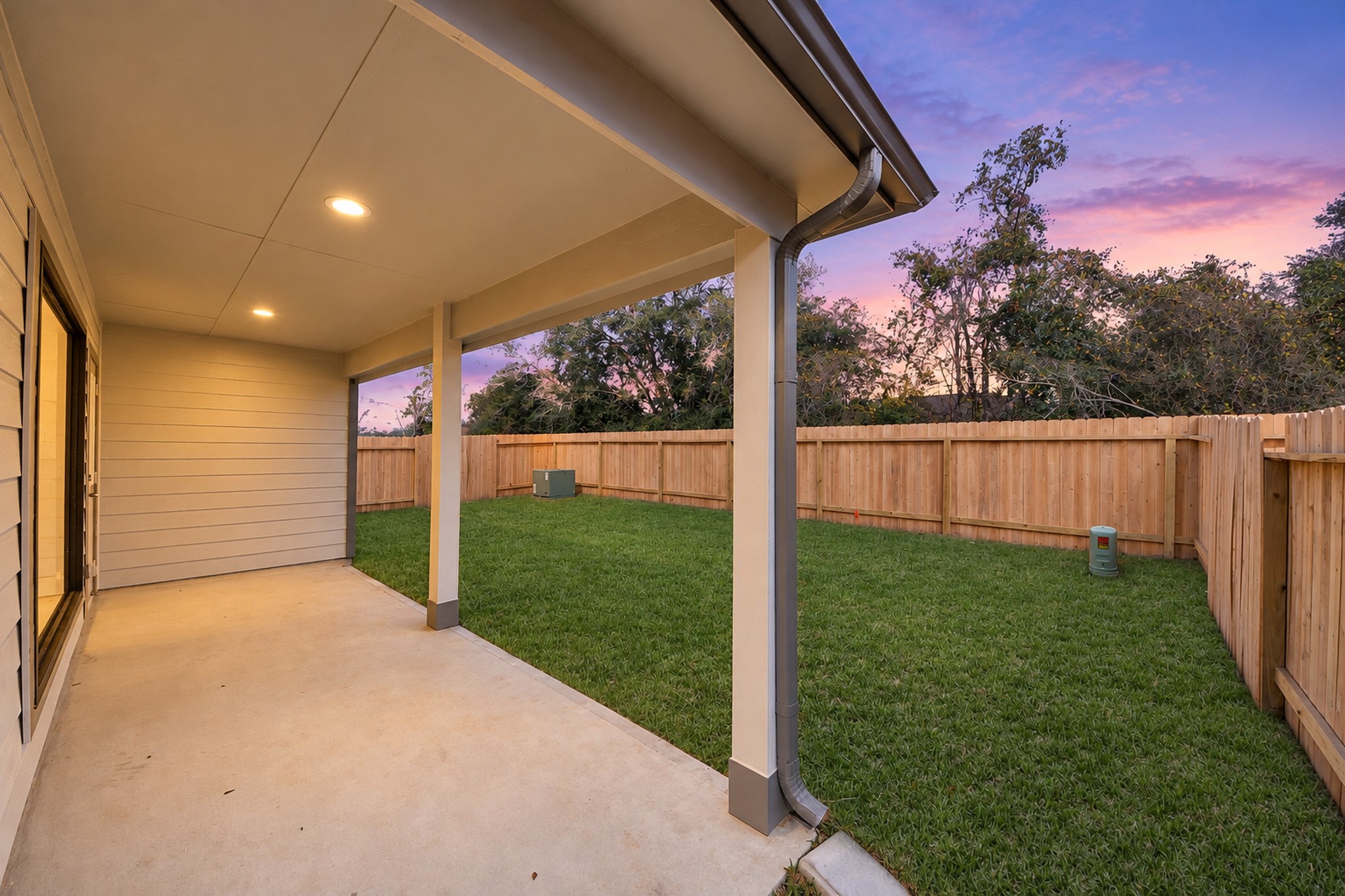 Spacious covered patio overlooking a lush, fenced backyard, perfect for outdoor relaxation and entertainment.