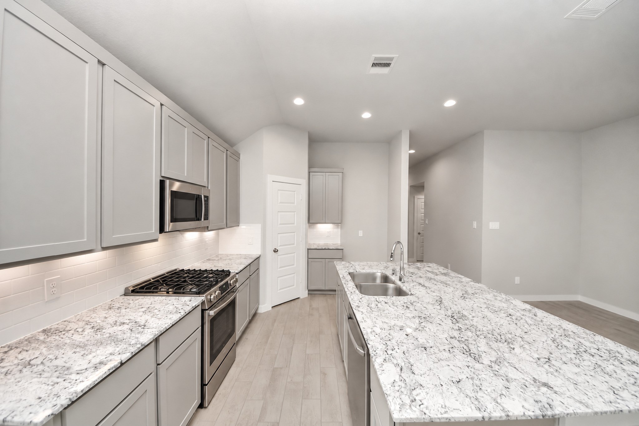Sleek kitchen with modern gray cabinetry, granite countertops, and stainless steel appliances, featuring a spacious island perfect for entertaining. Sleek kitchen with modern gray cabinetry, granite countertops, and stainless steel appliances, featuring a spacious island perfect for entertaining.