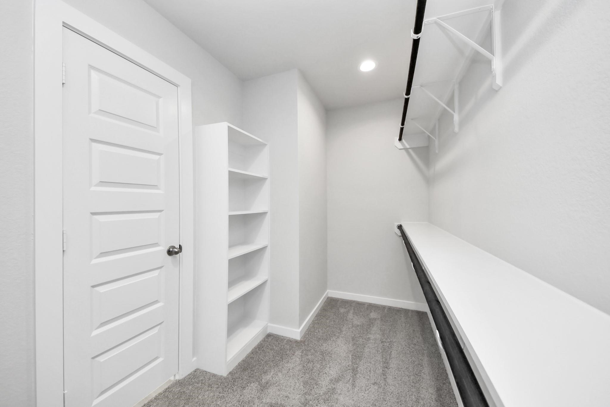 Spacious walk-in closet with built-in shelving and ample hanging space, perfect for organized storage.