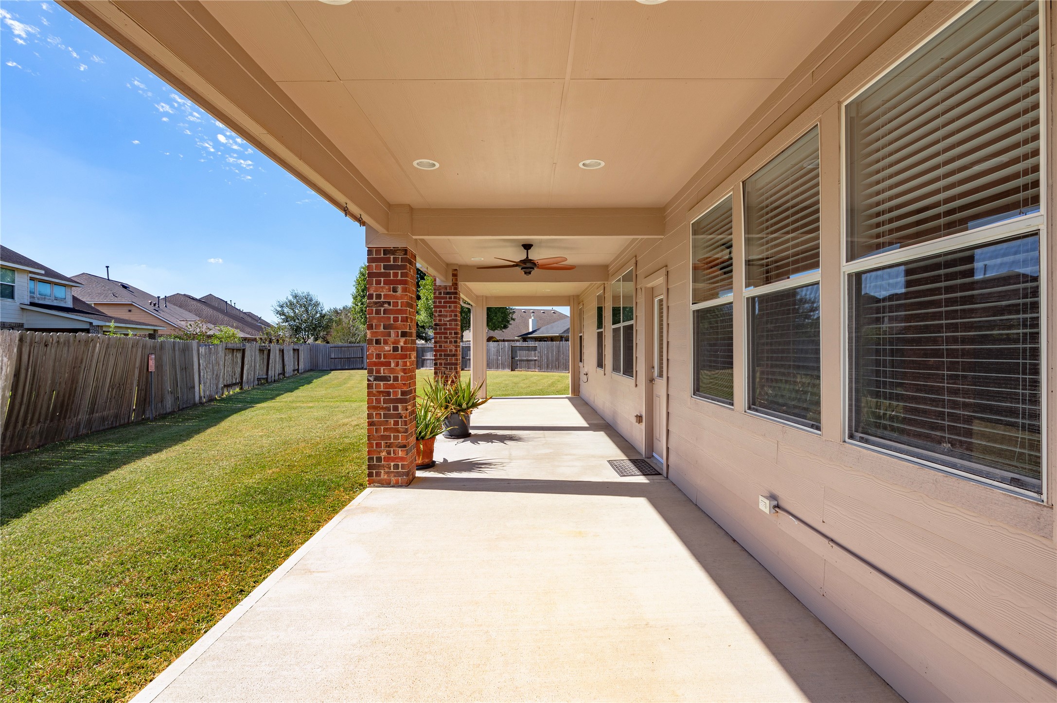 The large covered back patio with brick columns stretches along the back of the home.