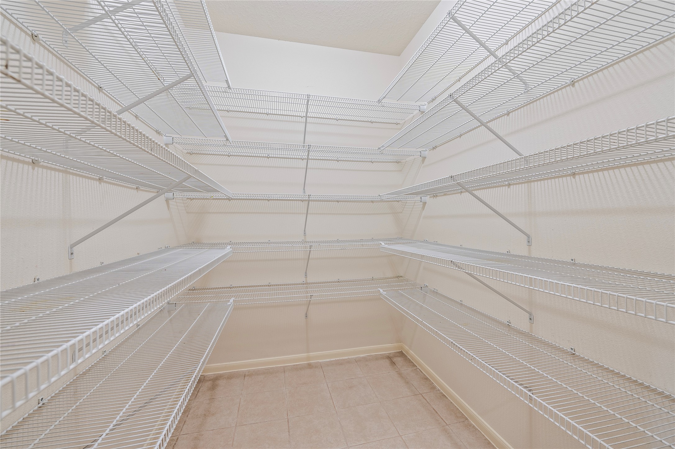 The large walk-in pantry offers abundant shelving and tile flooring.