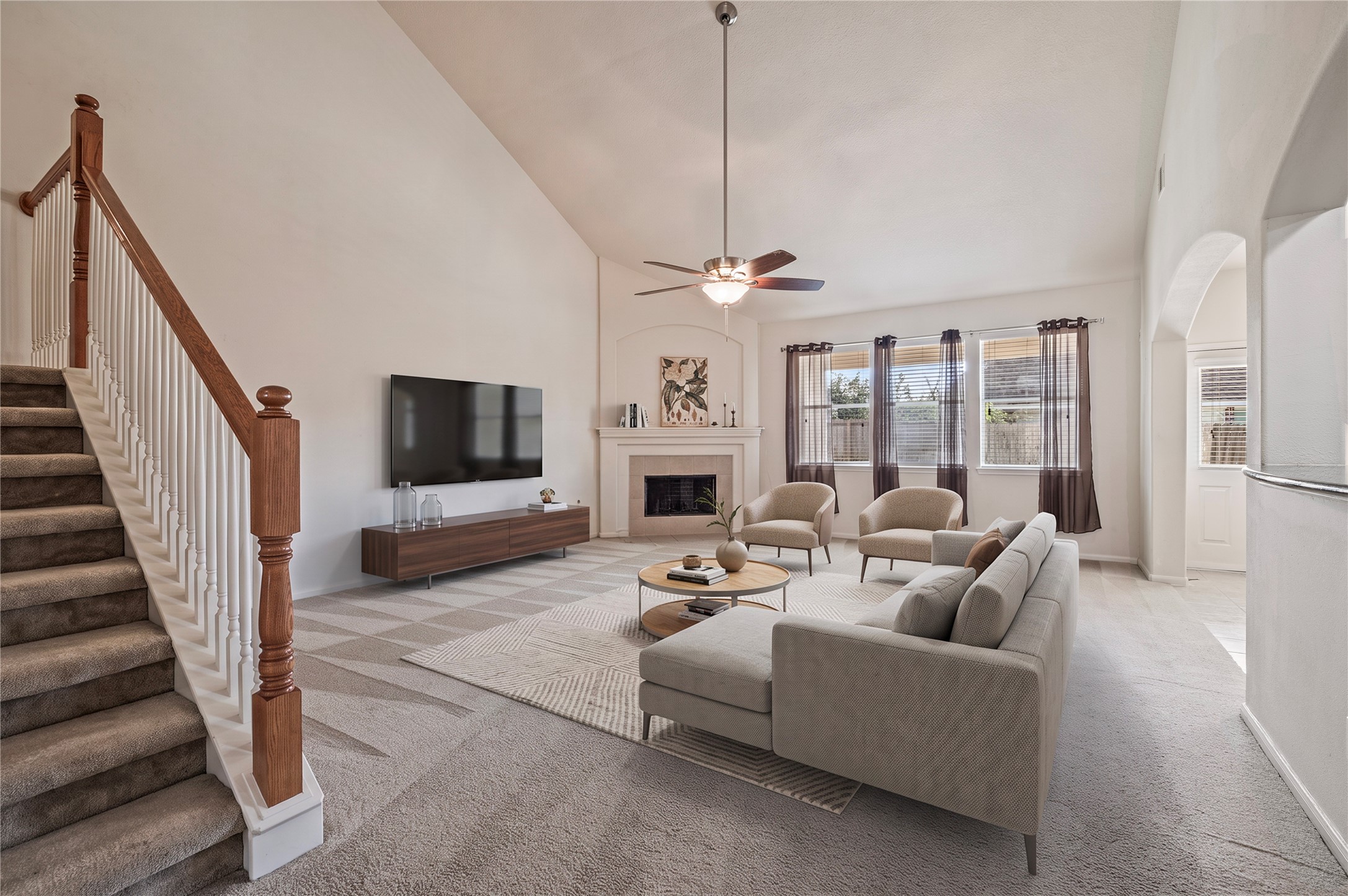 The grand family room features soaring ceilings, a ceiling fan and views of the large backyard. Room is virtually staged.