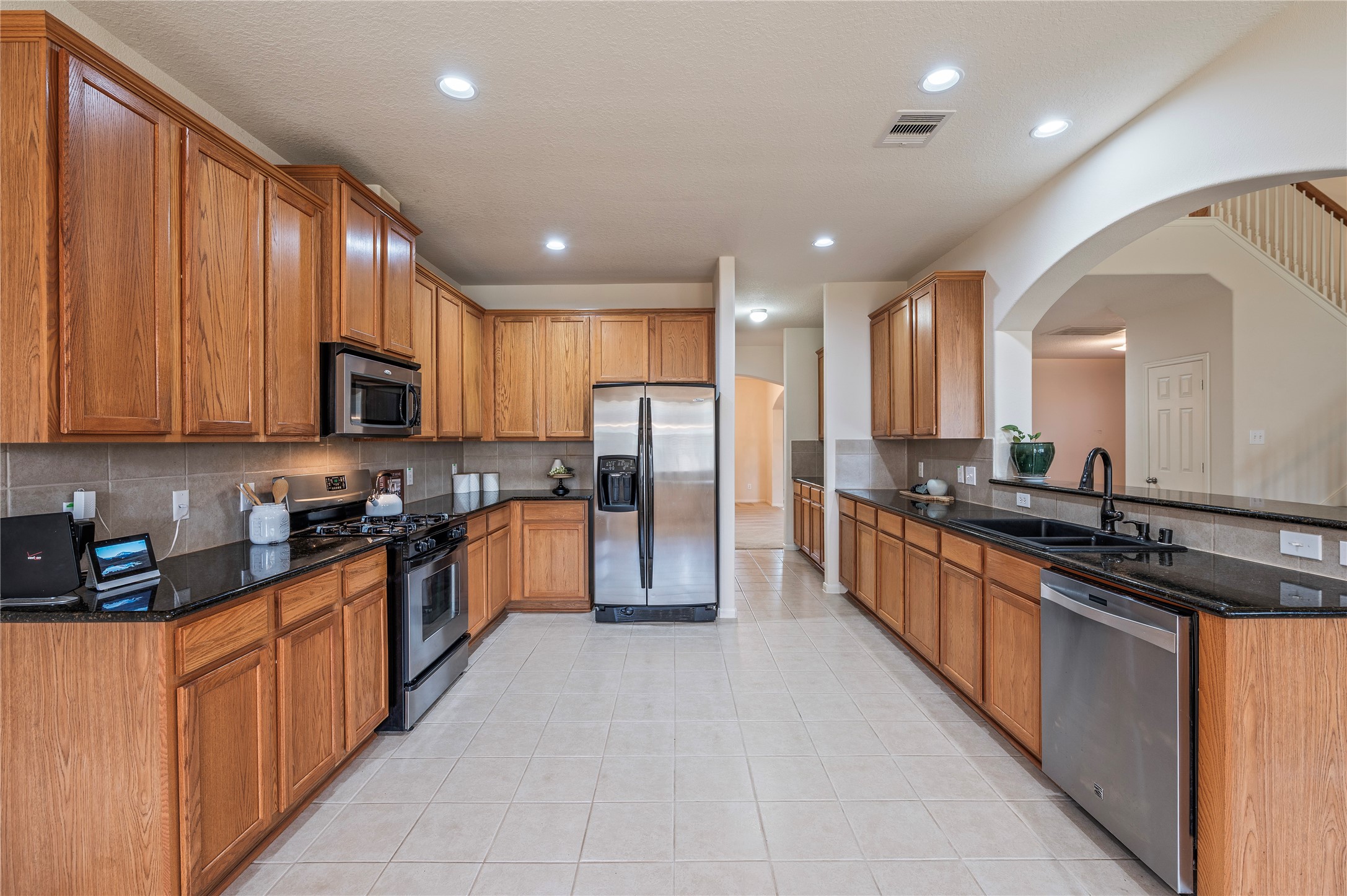 The kitchen features dark granite countertops, rich stained wood cabinetry and tile flooring.