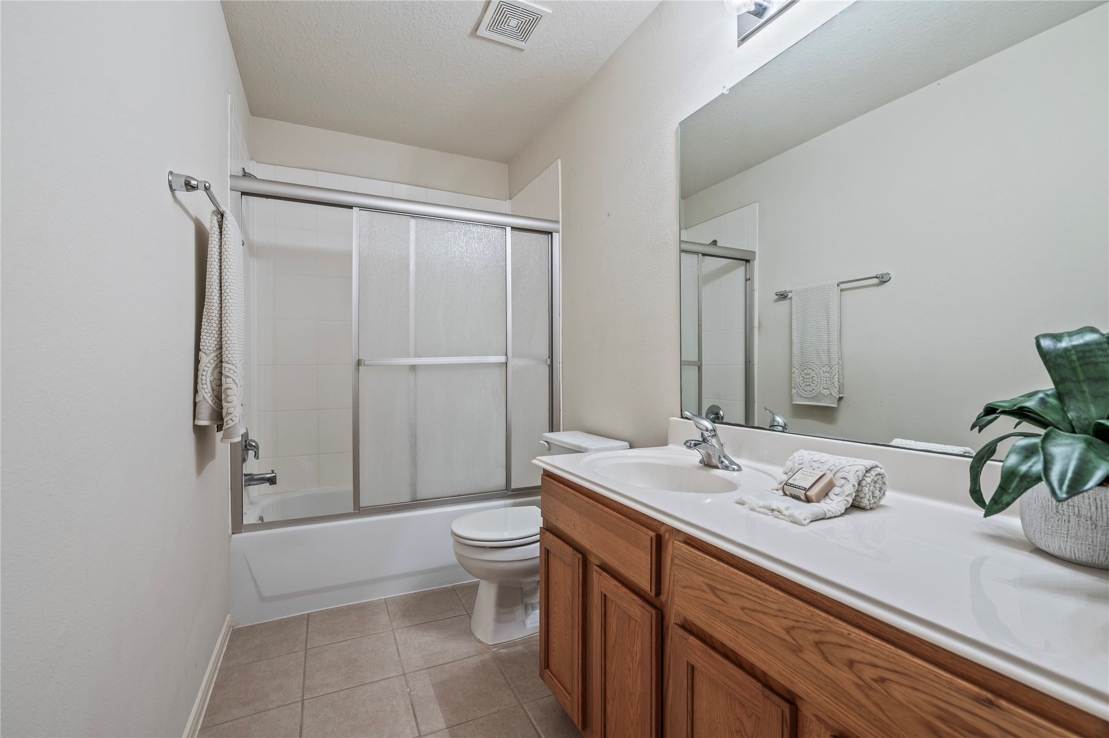 The third full bath, also upstairs, offers a large vanity, tile flooring and a shower with glass sliding doors.