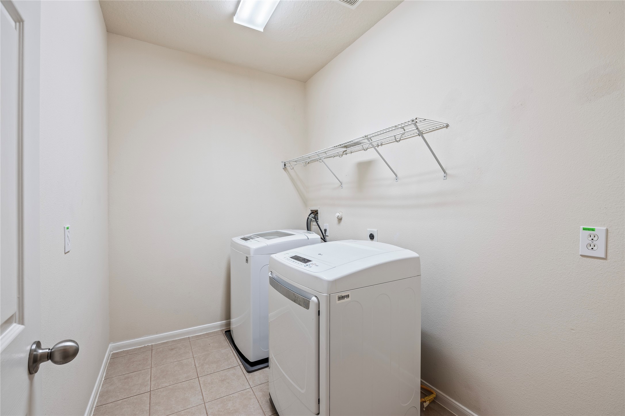 The large first-floor utility room with tile flooring has connections for gas or electric dryers.