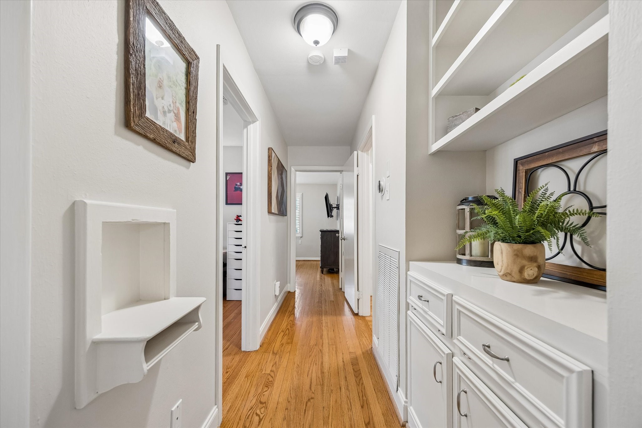 Hallway shelving and lower cabinets add storage along the route to the bedrooms. Open shelves and enclosed cabinetry provide space for books, linens and household essentials while keeping the passage clear.