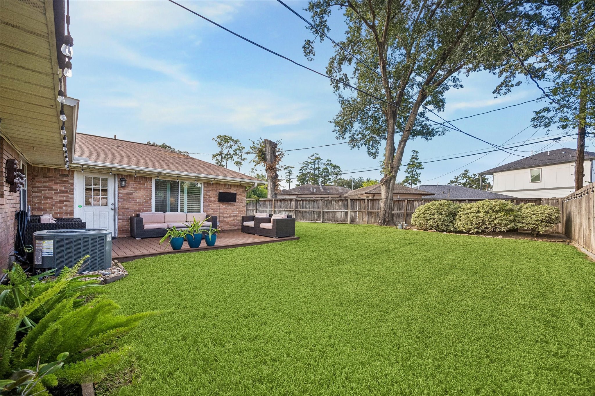 Mature tree and a broad fenced lawn give the backyard an inviting setting. Deck space alongside the house leaves room for outdoor recreation, gardening and gathering while offering different perspectives across the yard.