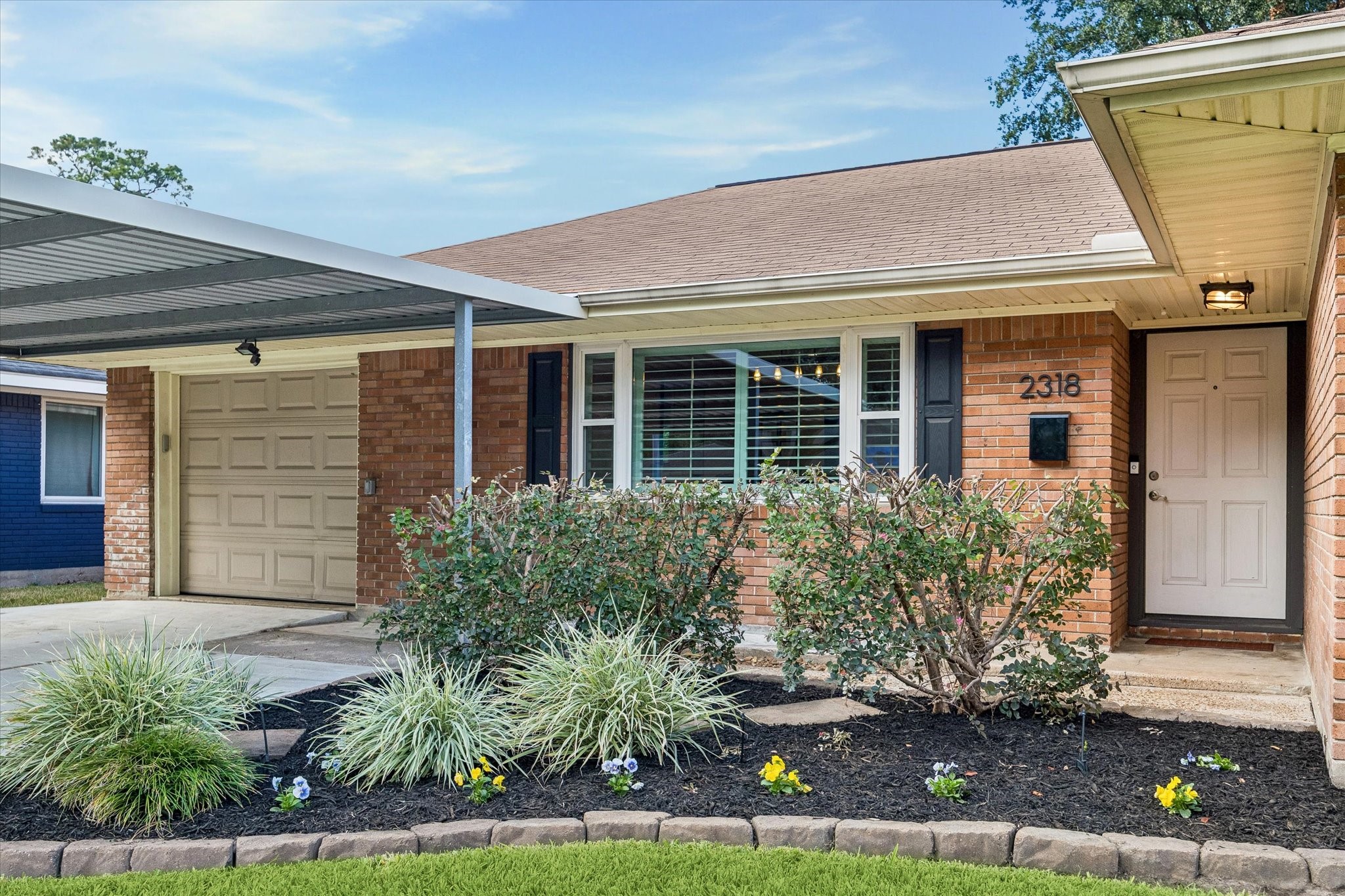 Landscaped beds frame the sheltered front entry and complement the home's classic brick exterior. Covered access creates a welcoming transition indoors, with an attractive front yard adding to the appeal from the street.