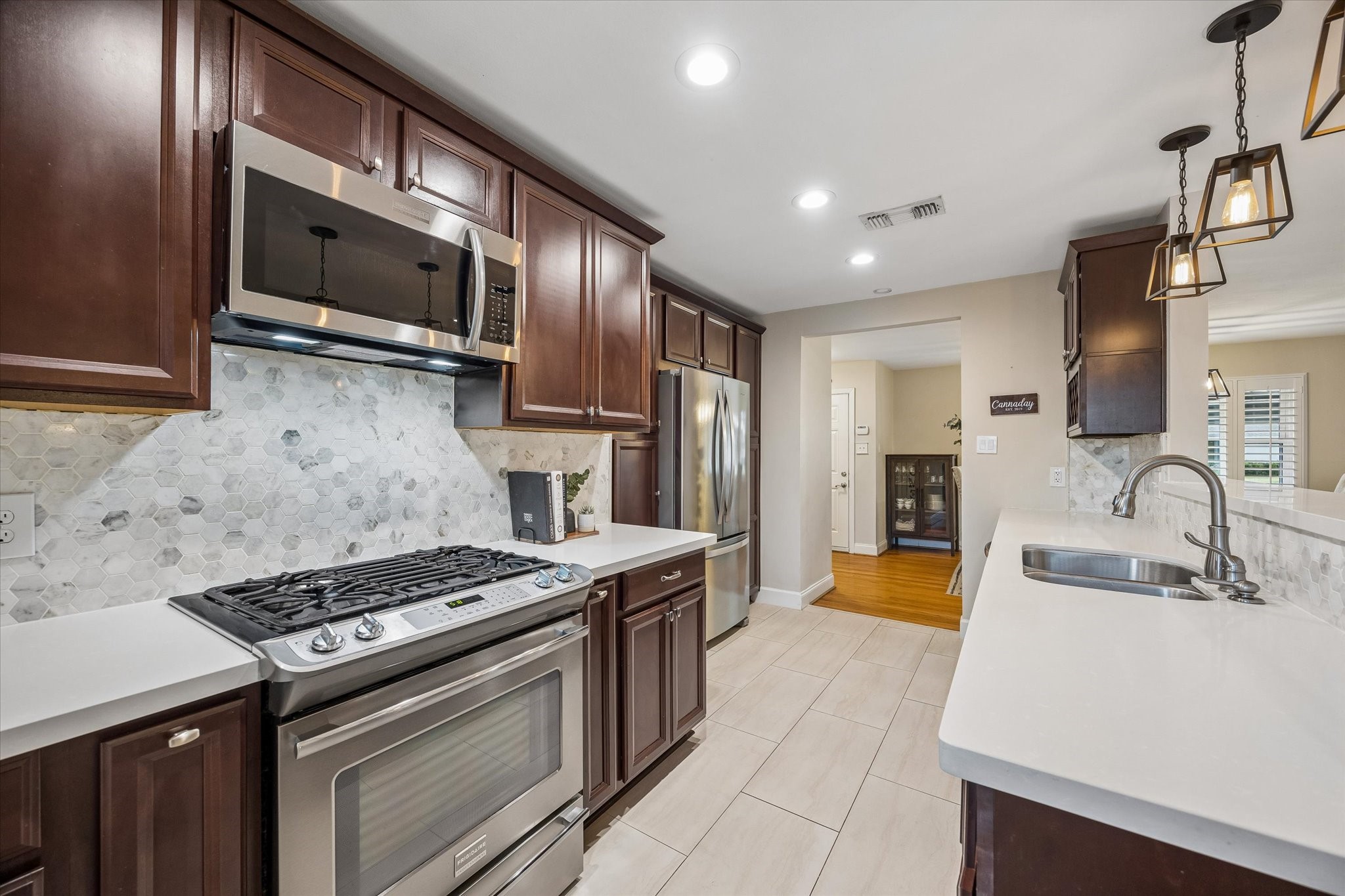 Gas range, microwave and surrounding counters create a convenient cooking area. Cabinet storage keeps essentials nearby, while the kitchen's open connection to adjacent rooms makes serving meals straightforward.