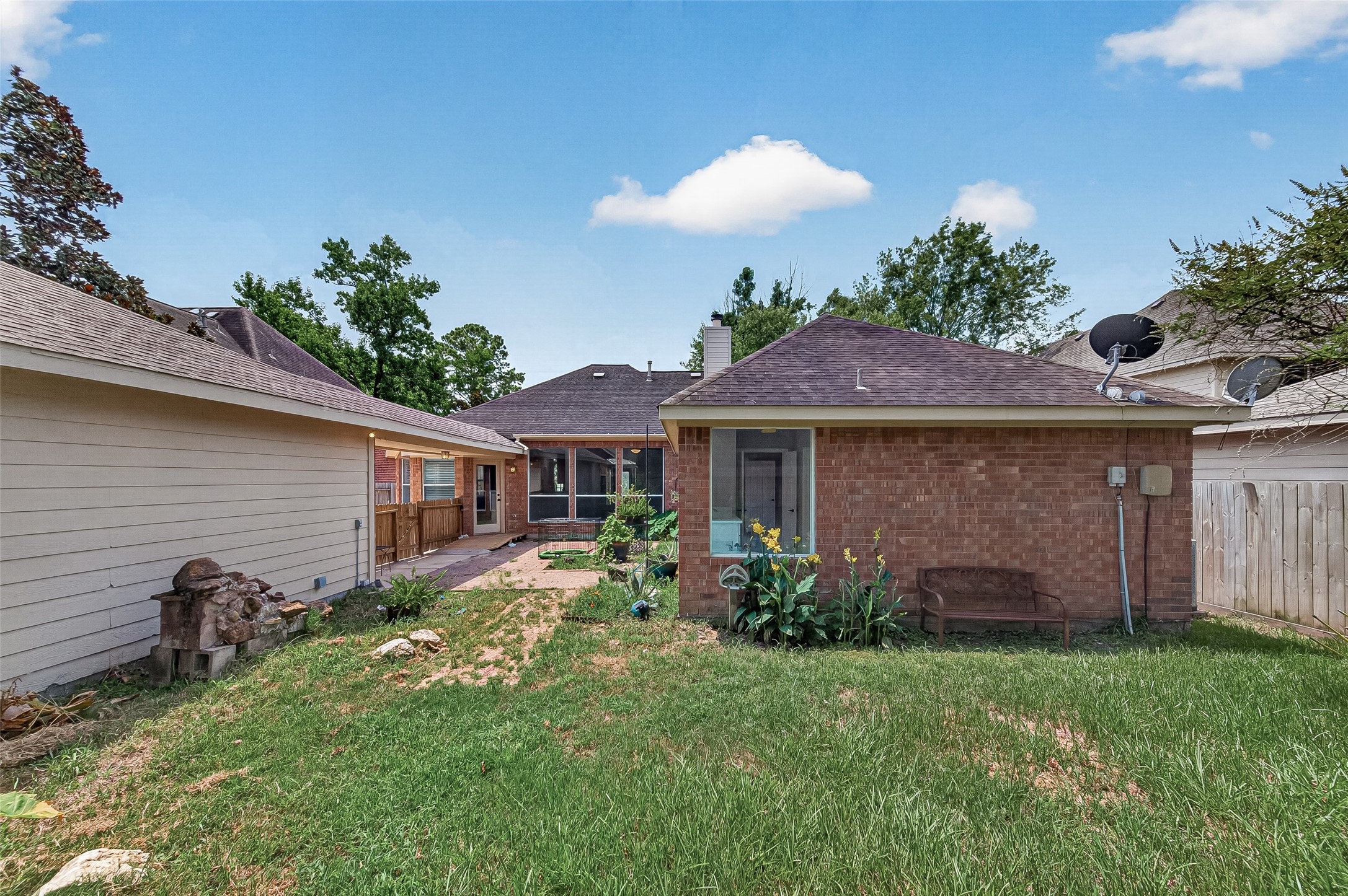 Charming backyard view with a brick exterior, inviting patio, and vibrant greenery, perfect for outdoor relaxation and entertaining.