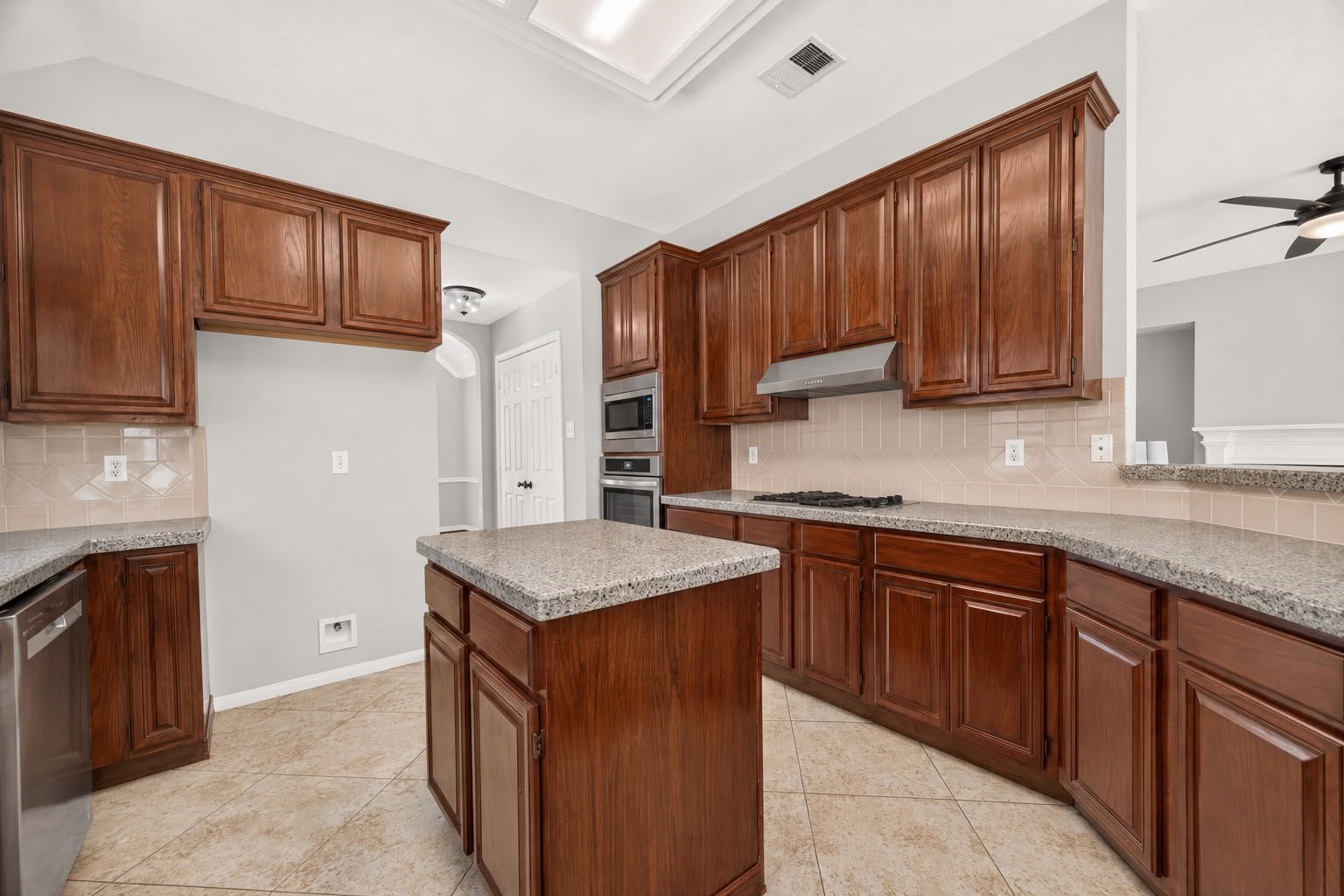 Spacious kitchen featuring rich wooden cabinetry, sleek granite countertops, and modern stainless steel appliances, perfect for culinary enthusiasts.