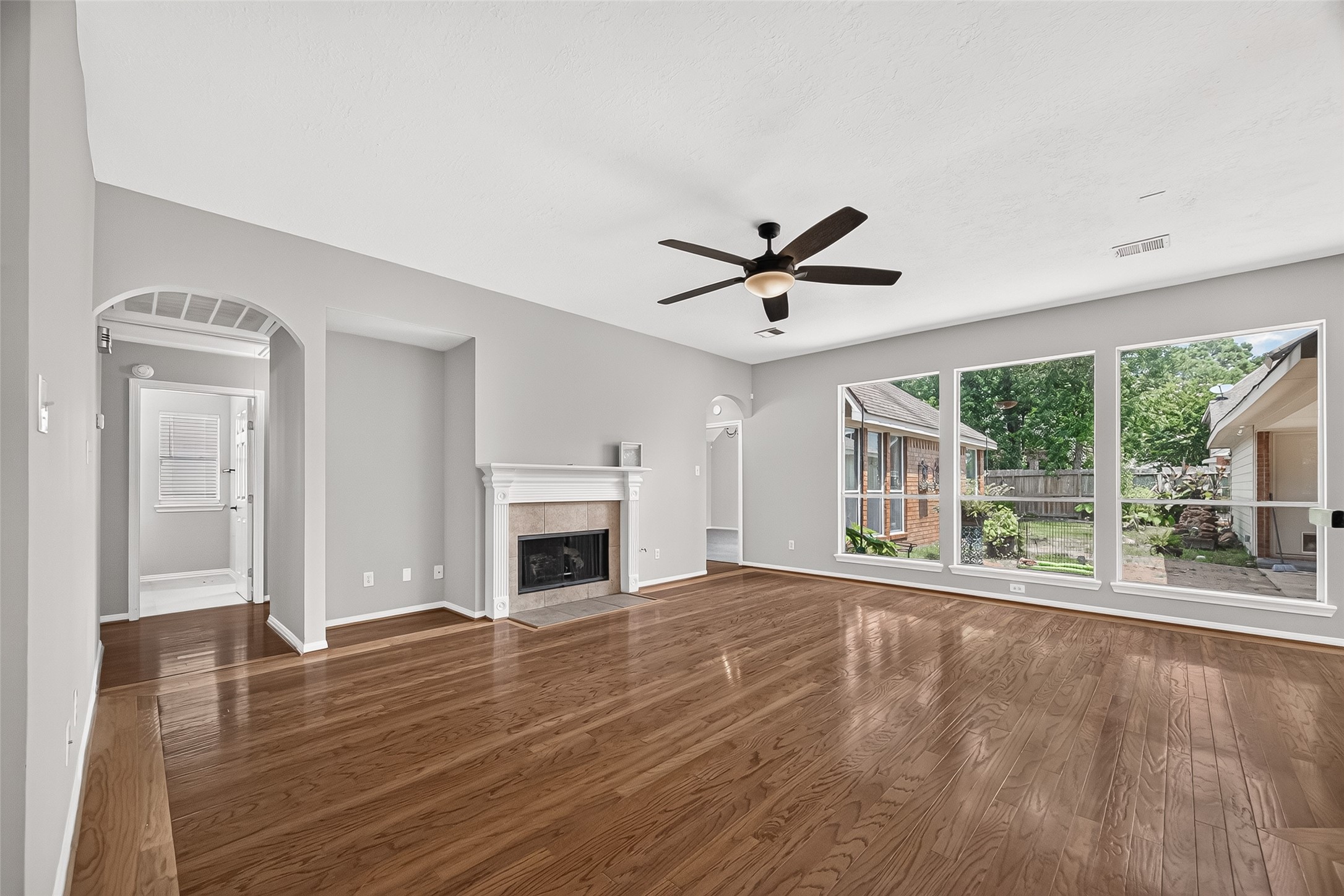 Spacious living room featuring elegant hardwood floors, a cozy fireplace, and large windows with views of the backyard, creating a bright and inviting atmosphere.