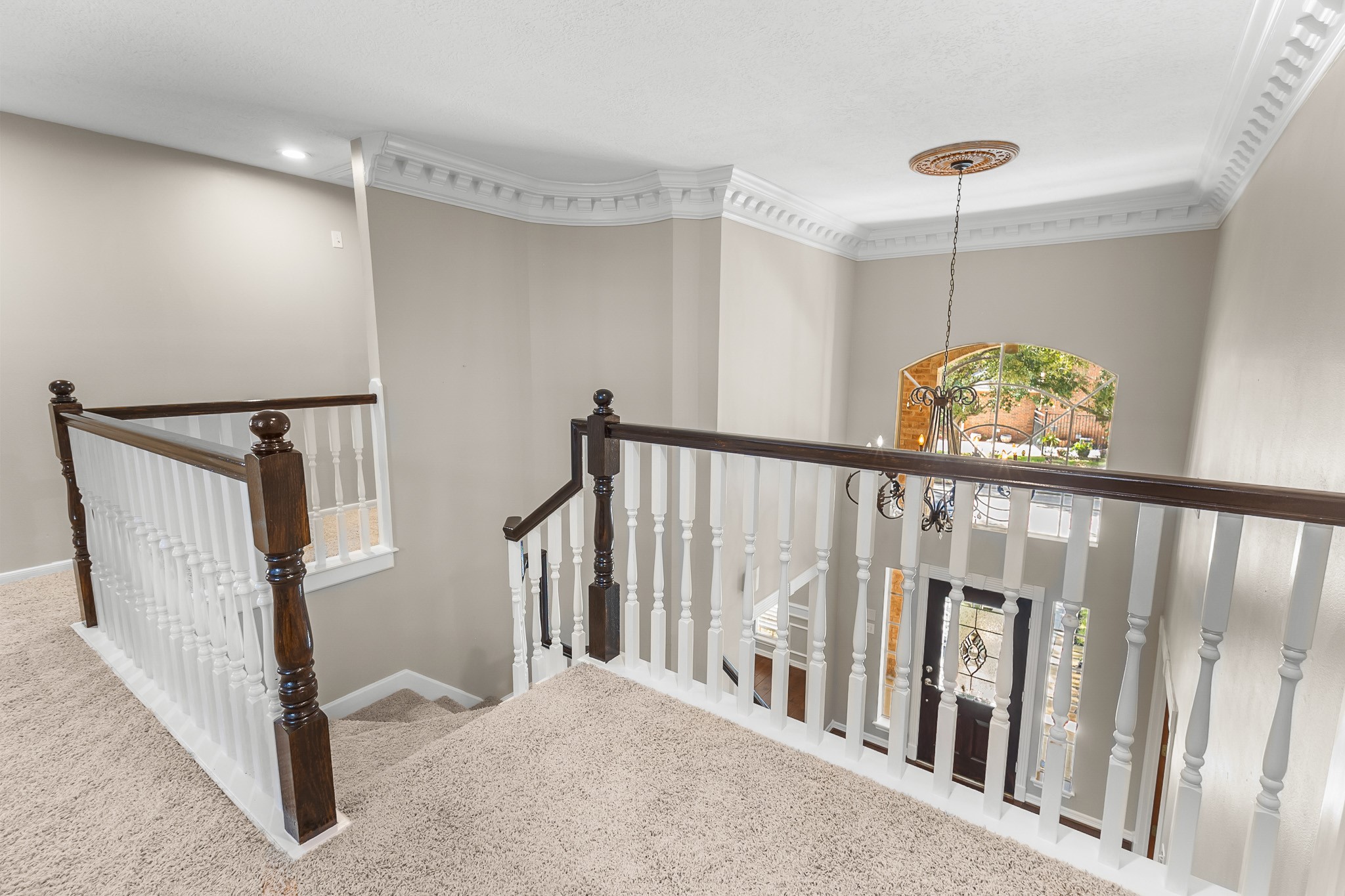 The upper-level landing overlooks the foyer, with contrasting wood railings and white balusters continuing the homes traditional character.