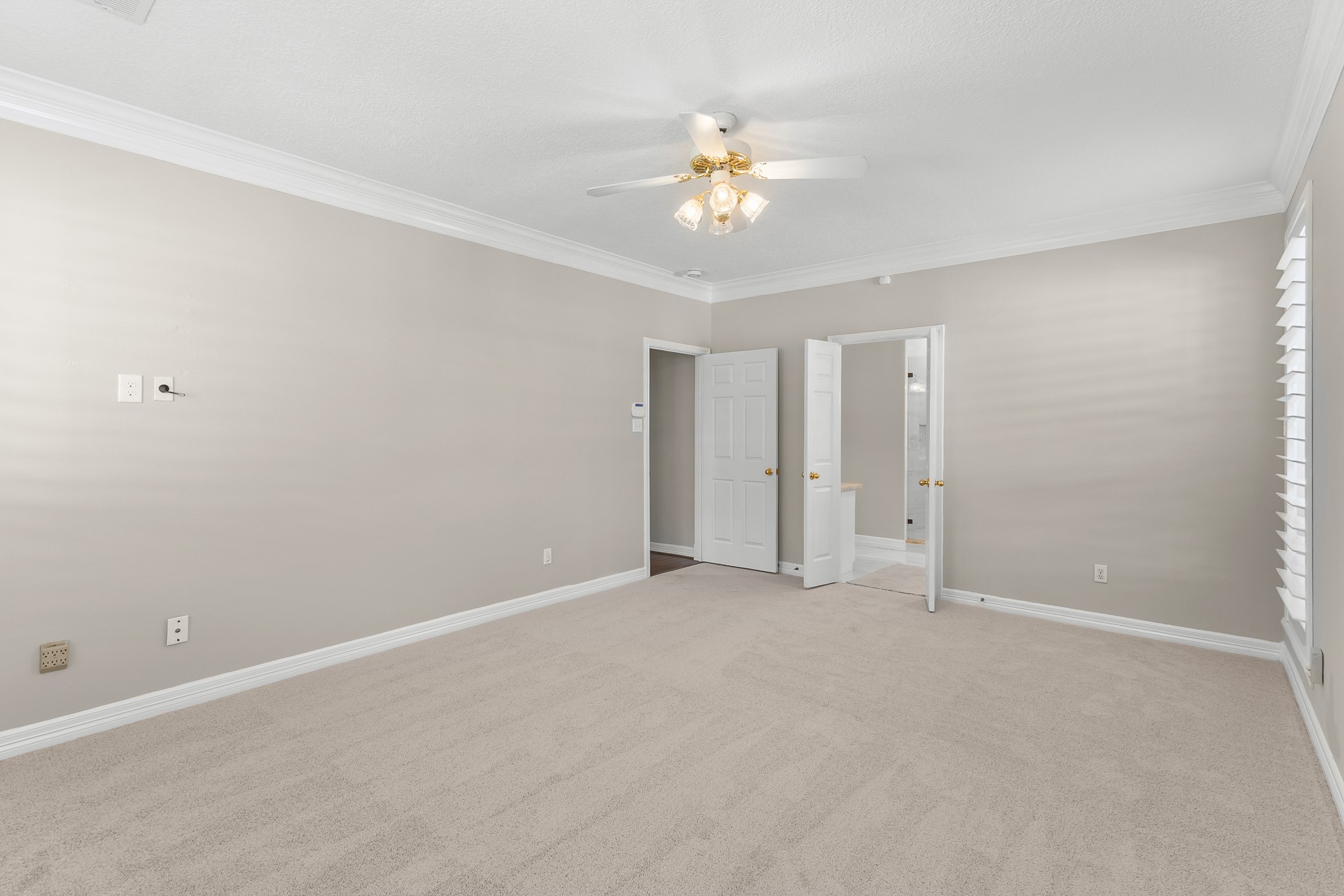 The primary suite offers generous proportions and a calm neutral palette, with convenient access to the adjoining bath and closet areas.