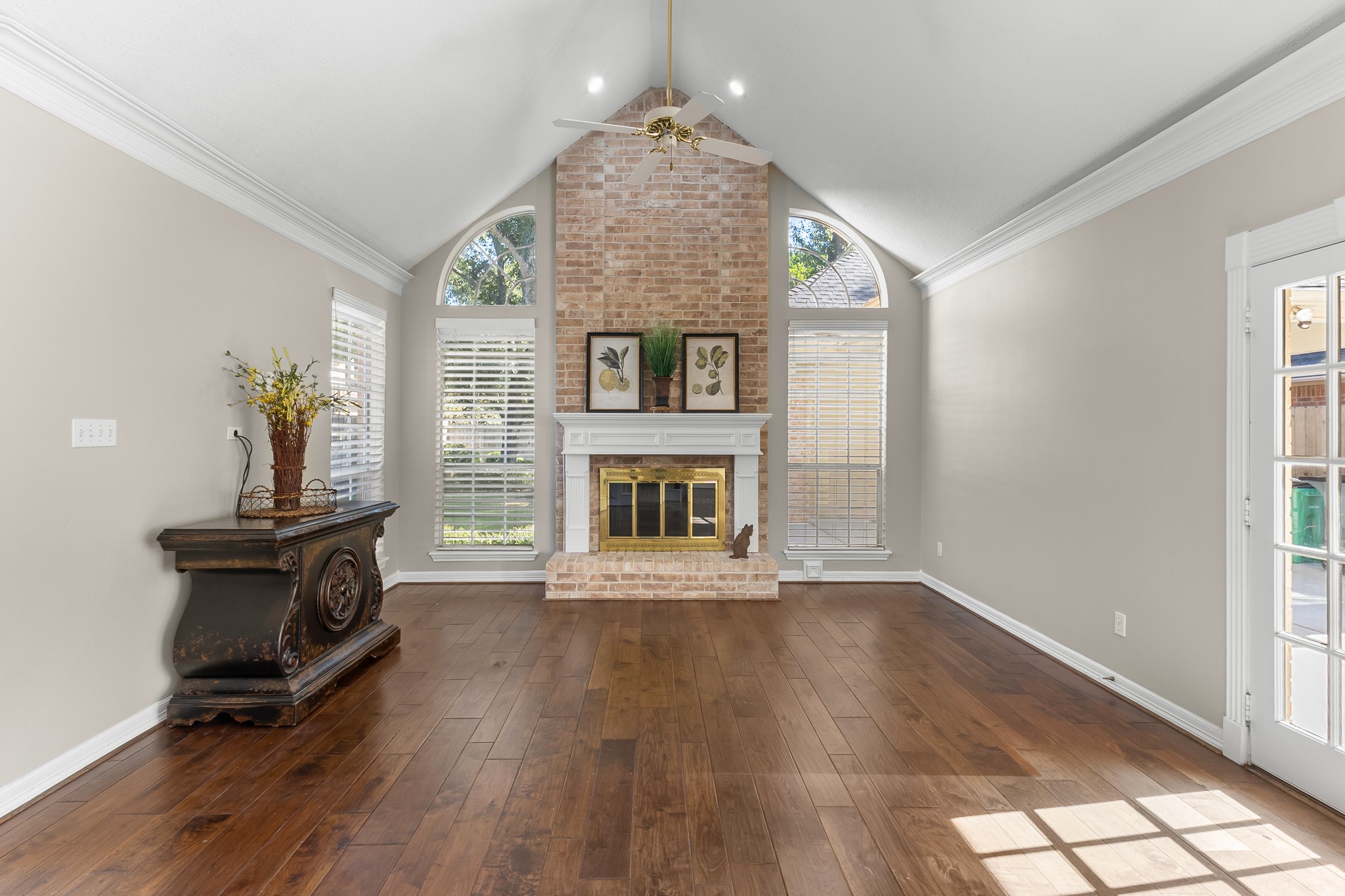 The substantial brick fireplace and graceful arched windows create a striking focal point filled with natural light.