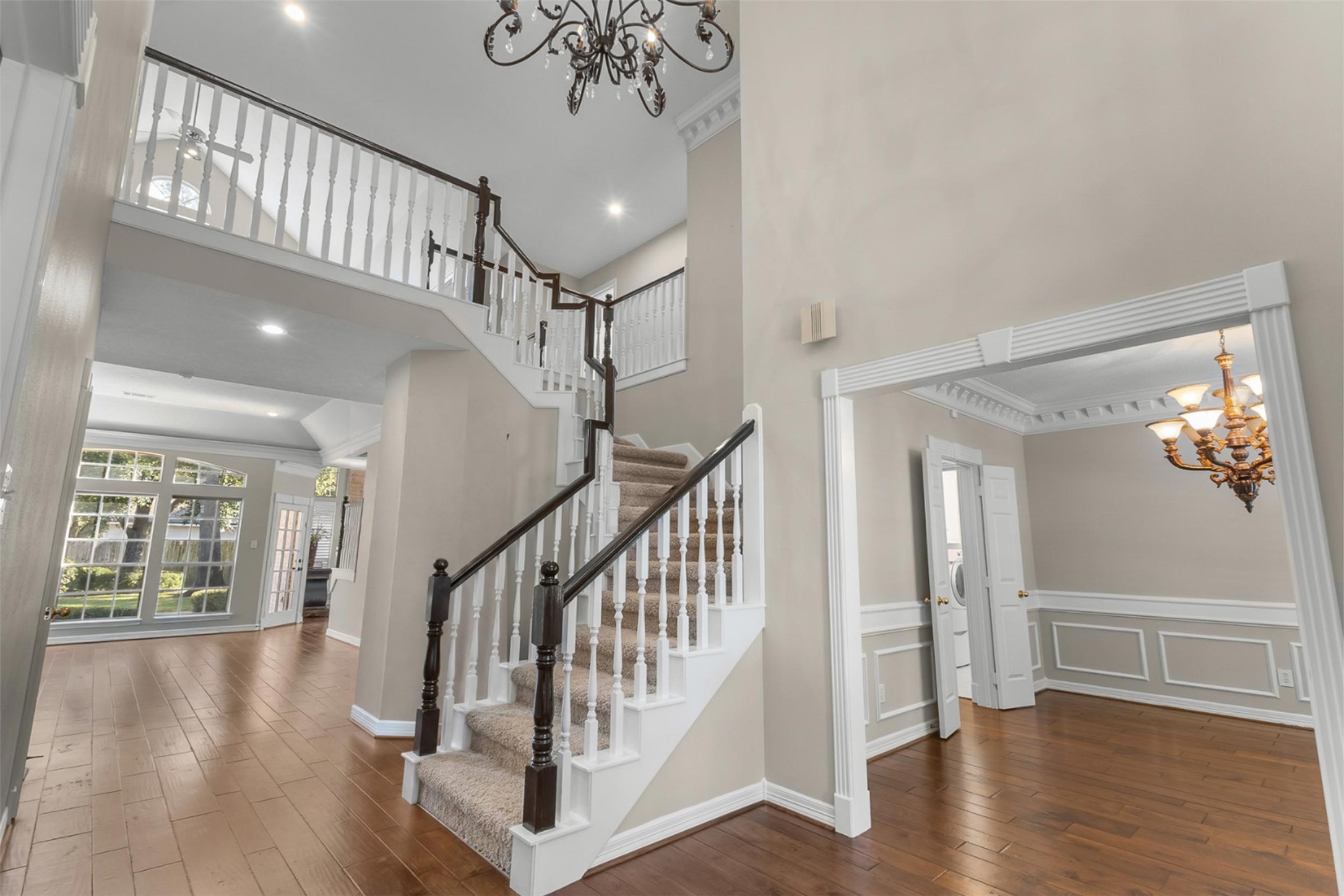 This unobstructed view seamlessly captures the open-concept flow from the grand entry through the formal dining and living rooms, while offering a warm, inviting peek into the spacious family room beyond.