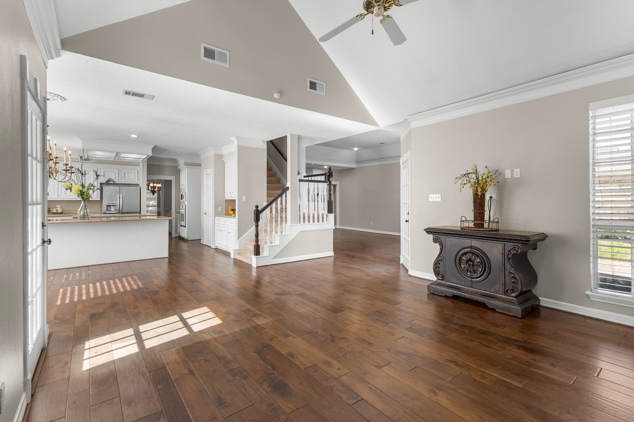 Vaulted ceilings and continuous wood flooring emphasize the sense of space, while the open layout connects the family room and kitchen.