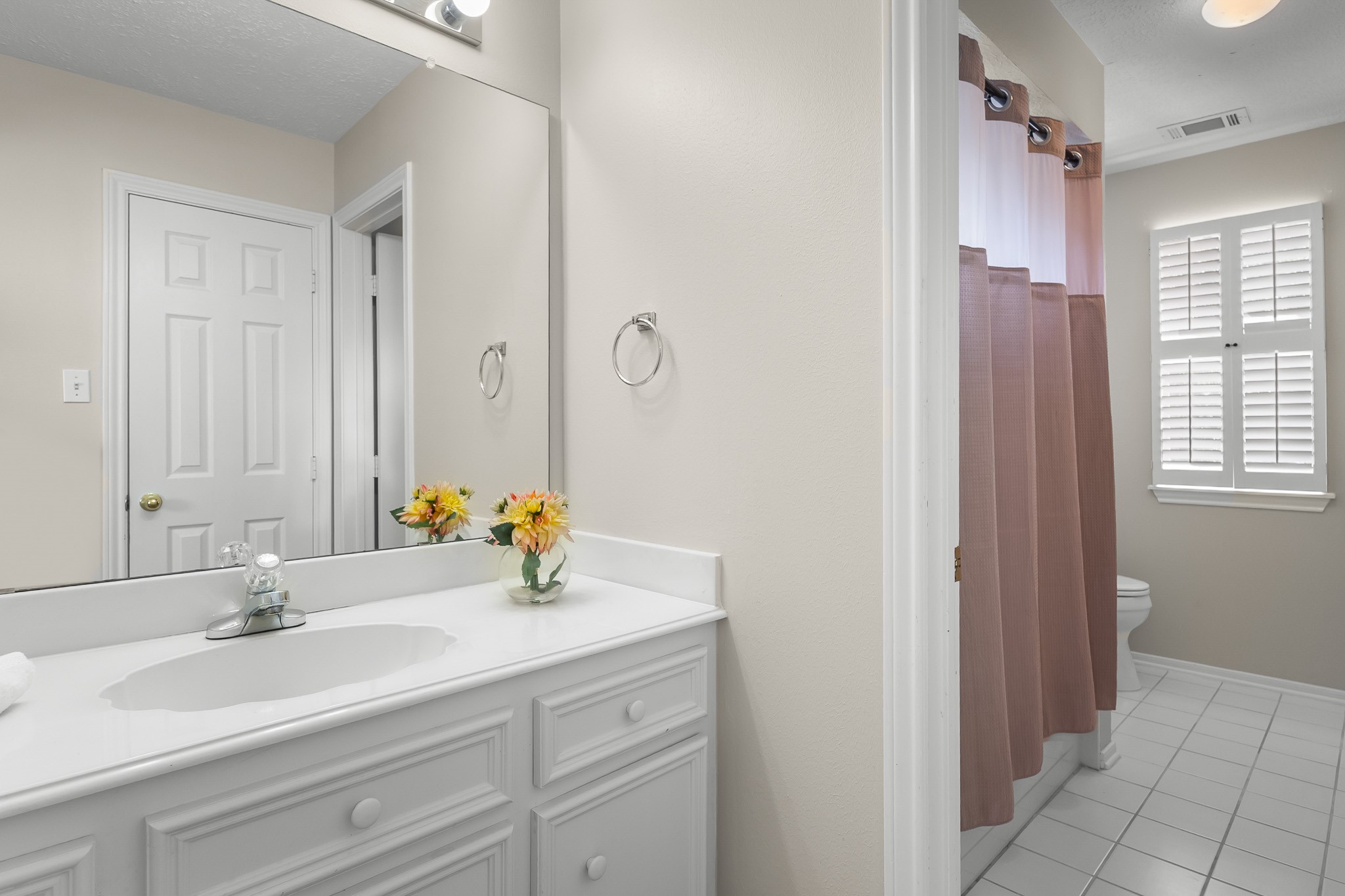 A bright bathroom pairs a white vanity with a tub-shower combination and timeless neutral finishes.