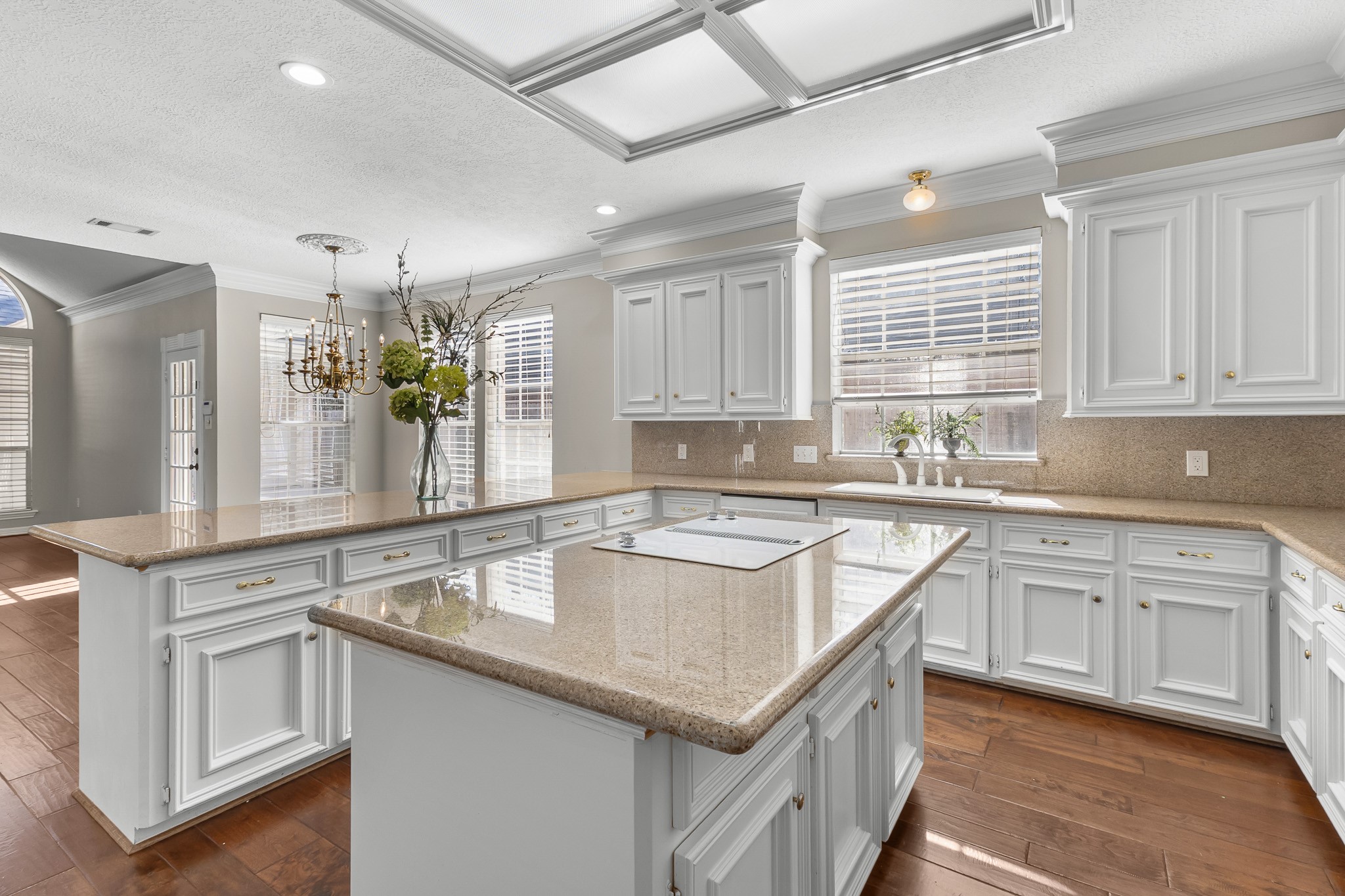 White cabinetry, generous granite work surfaces and a central island define a bright kitchen with classic appeal and abundant workspace.
