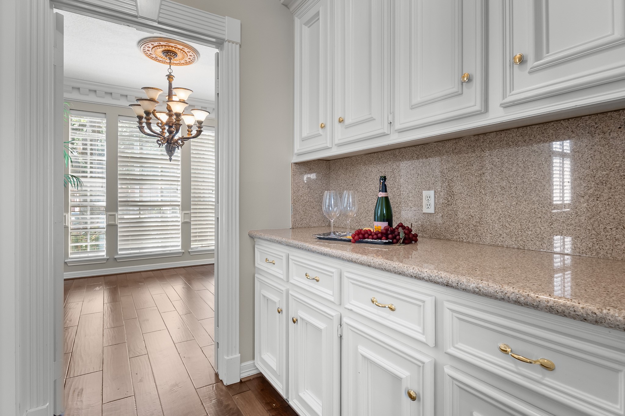 A dedicated butlers pantry pairs abundant white cabinetry with warm-toned counters for convenient serving and entertaining preparation.